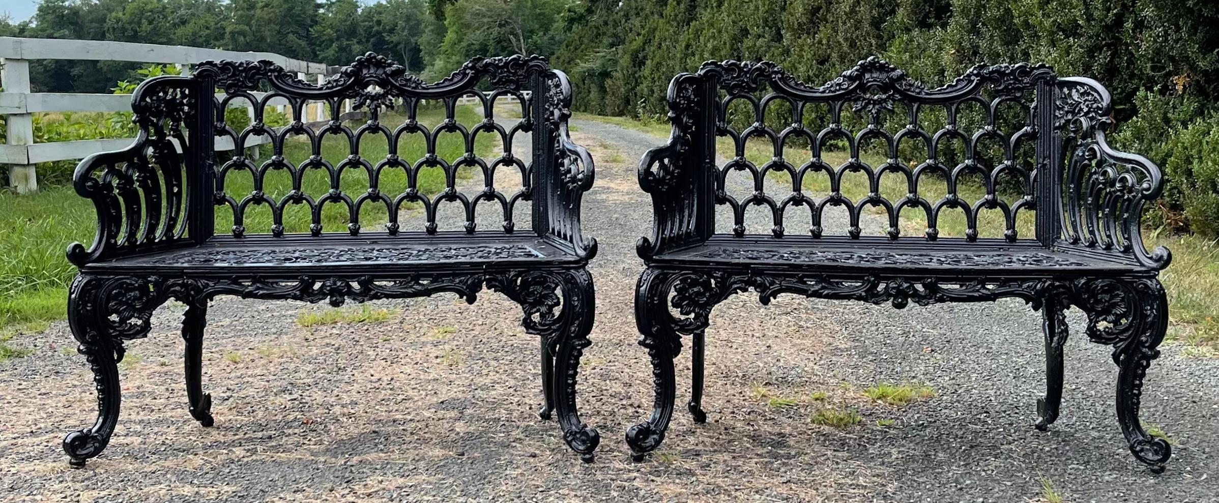 A pair of mid-19th century Scottish painted cast iron garden benches with scroll design and filigree seat with horseshoe motifs on back. Possibly Carron Co., Stirlingshire, circa 1846.
