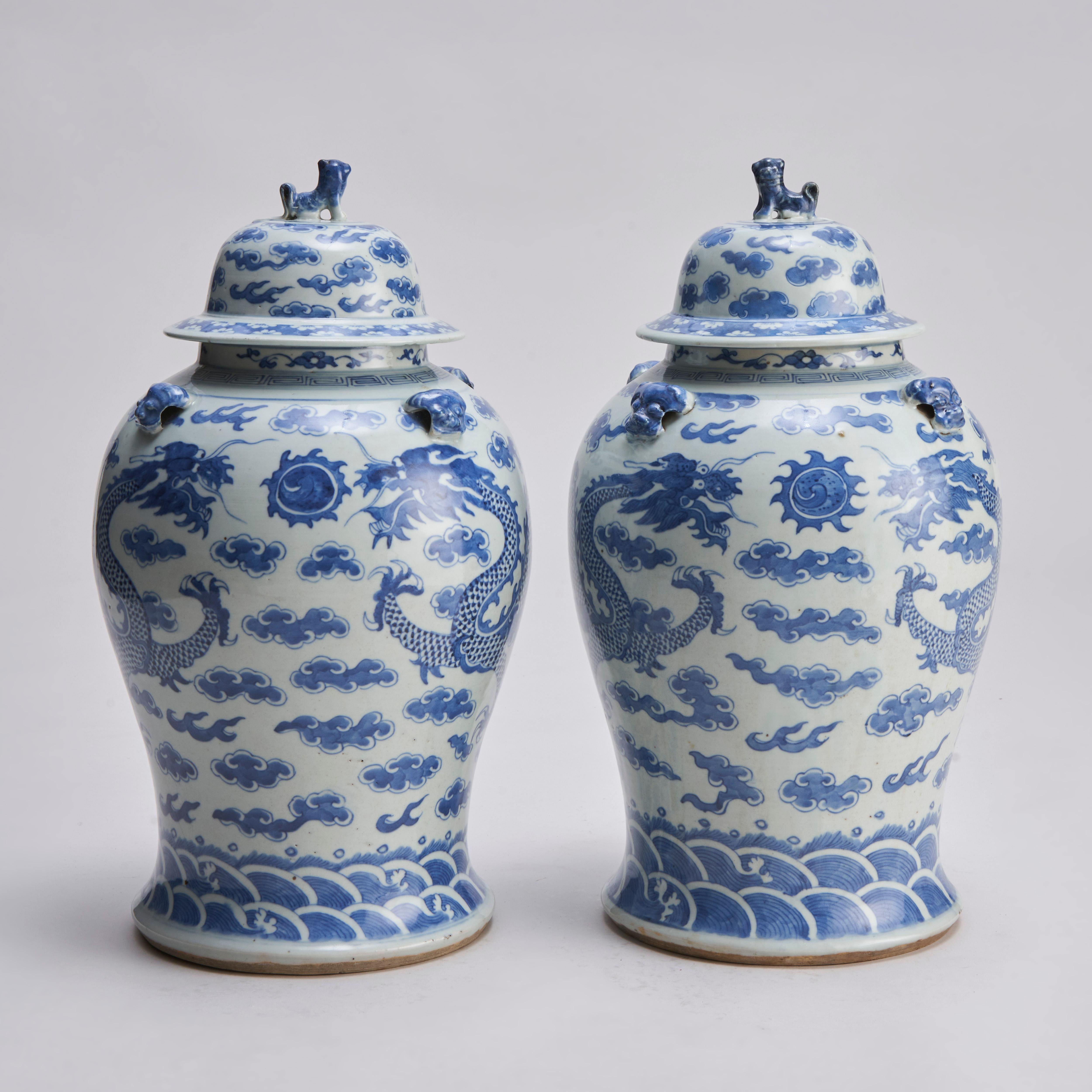Paire de jarres et de couvercles chinois en bleu et blanc du XIXe siècle, avec des têtes de chien Shi Shi et un décor moulé de chien Shi Shi sur les épaules.

Les vases sont décorés de motifs assortis de dragons poursuivant la perle flamboyante, sur