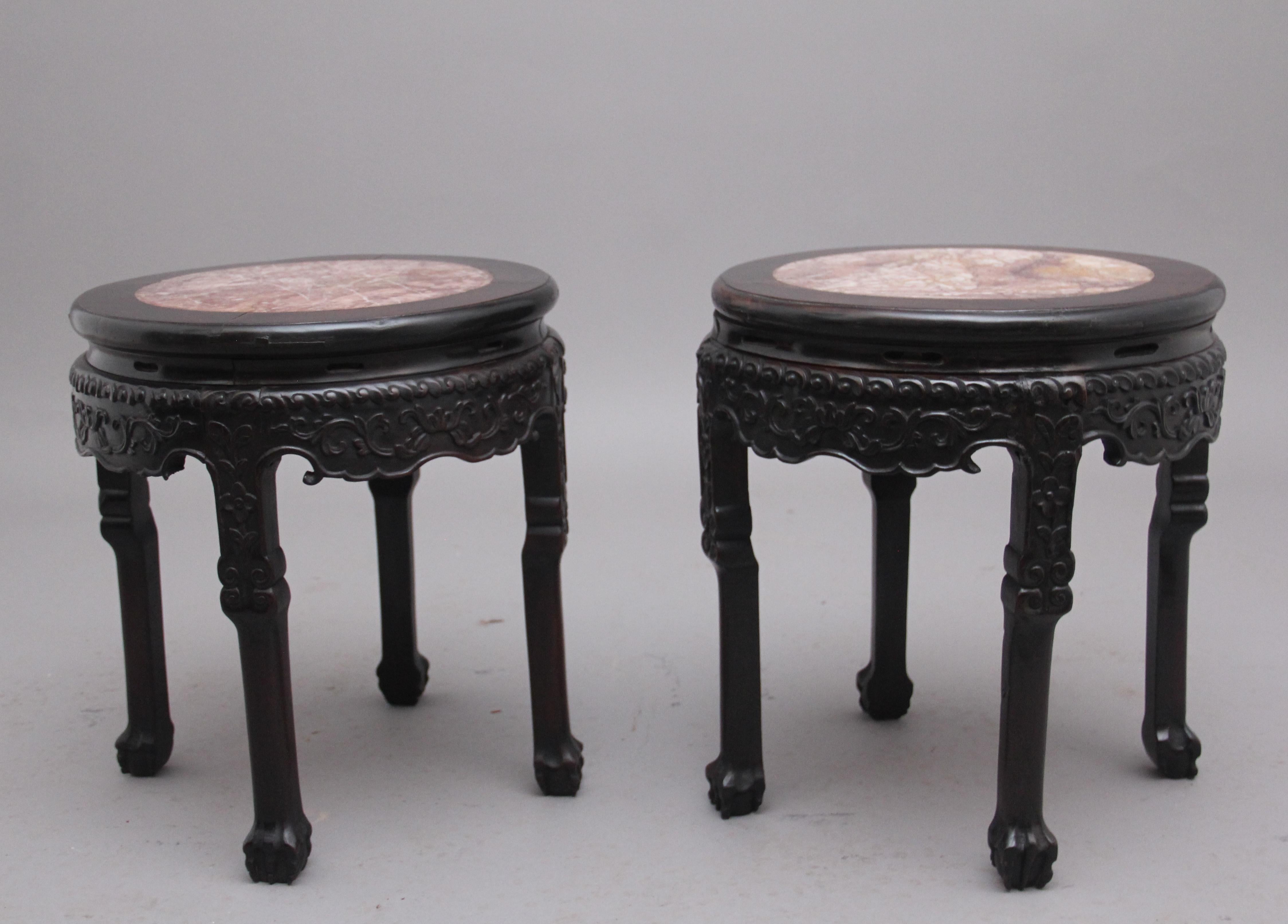 A pair of 19th Century Chinese carved hardwood occasional table, the circular shaped top with the original rose marble inserts with concave sides over a caved apron on all sides, raised on shaped legs terminating on ball and claw feet. Circa 1880.