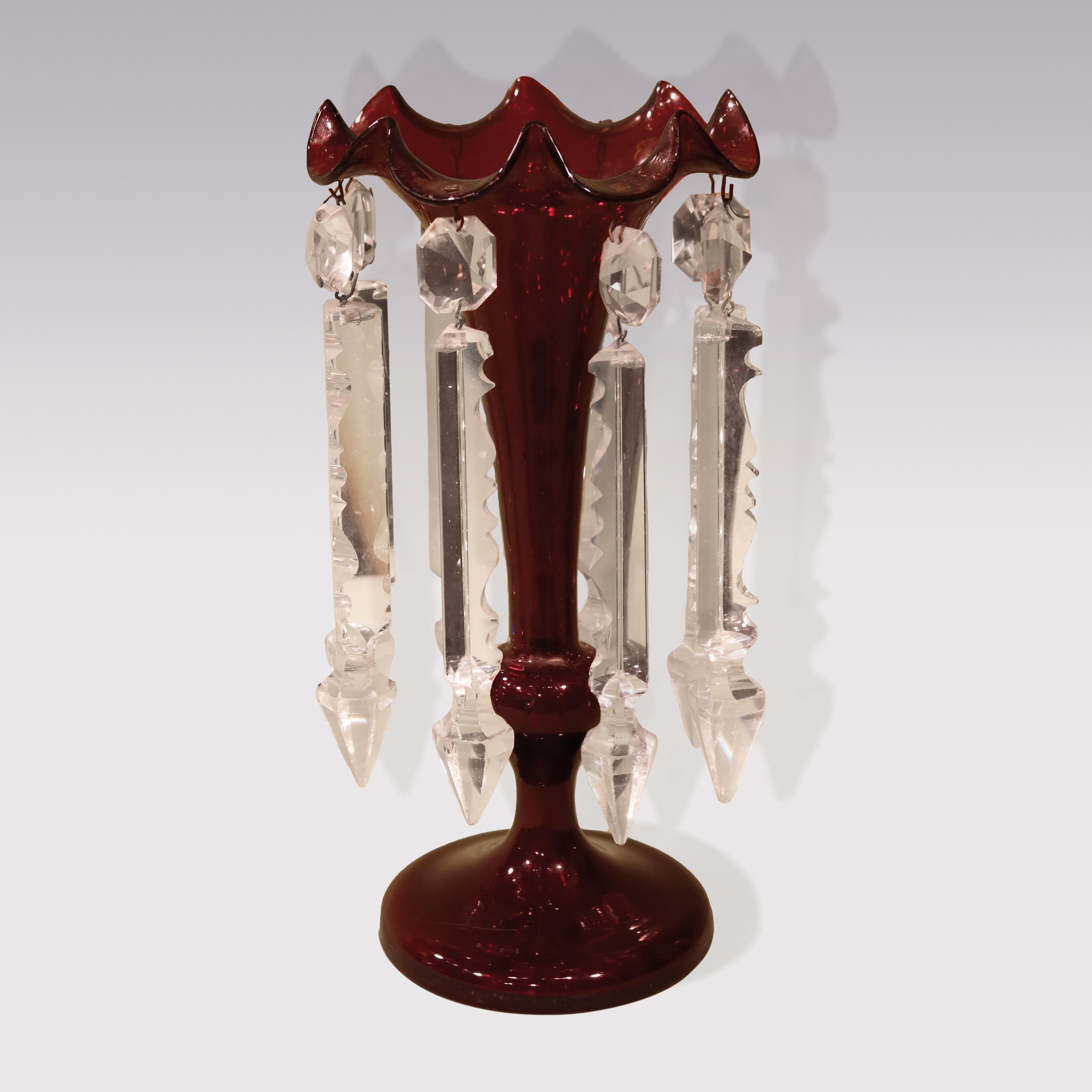 A pair of mid 19th century cranberry glass Vases, having scalloped tops holding cut-glass pendant drops raised on circular stems.