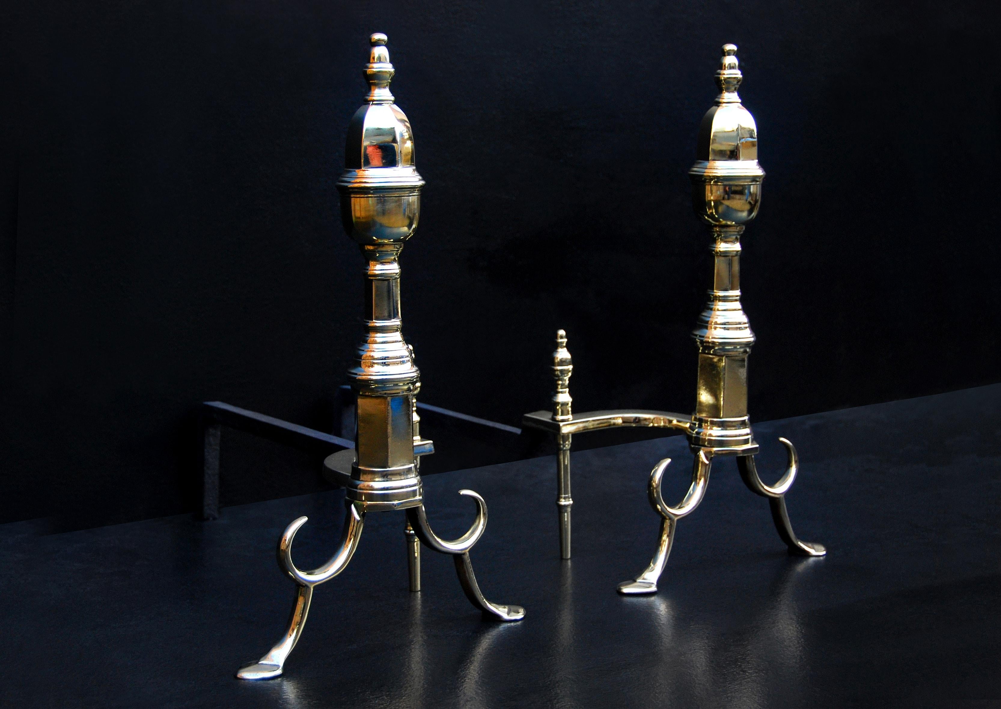 A pair of 19th century English brass firedogs. The shaped feet, surmounted by hexagonal shafts and finials above. Shaped backbars.

Height:	533 mm      	21