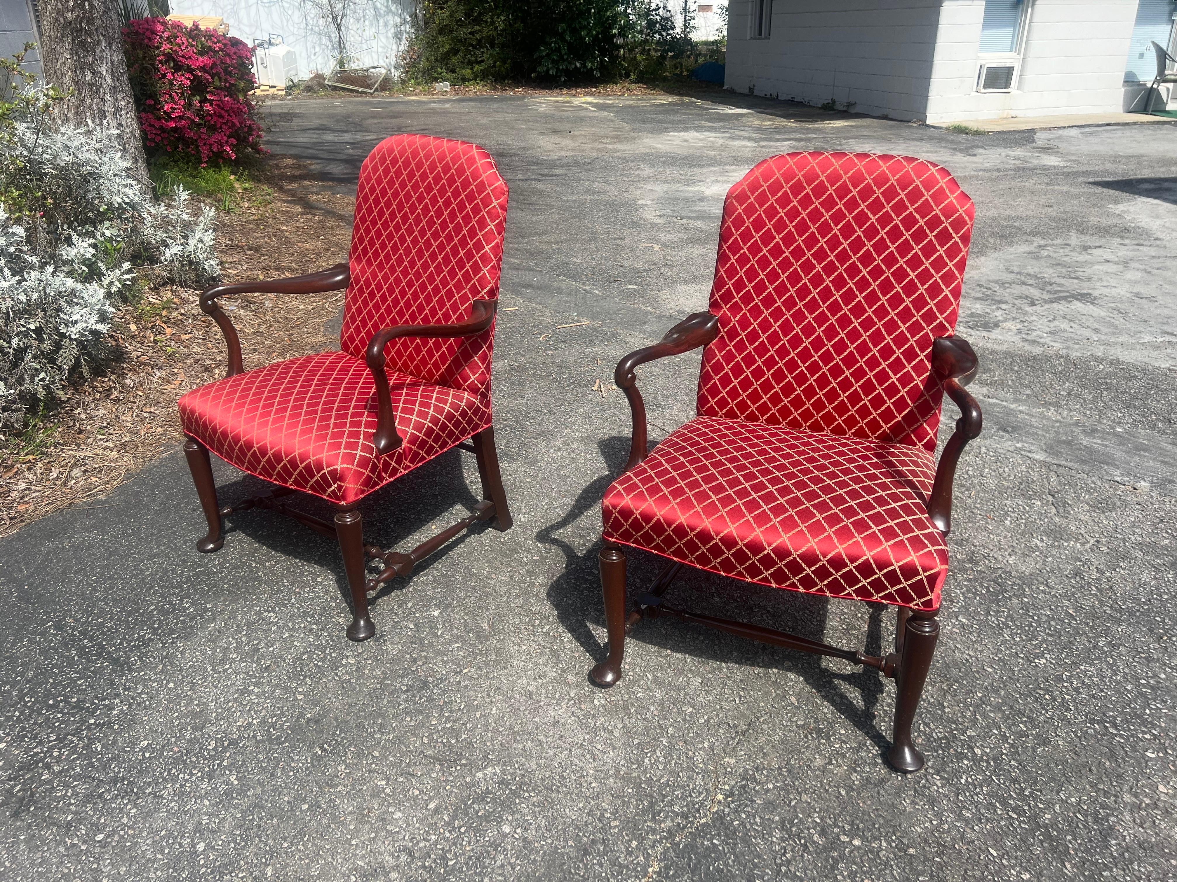 Humped back, upholstered to the back and seat in red fabric with a lozenge design, the arms of scrolling form, the legs joined by stretchers. In excellent condition commensurate of age.