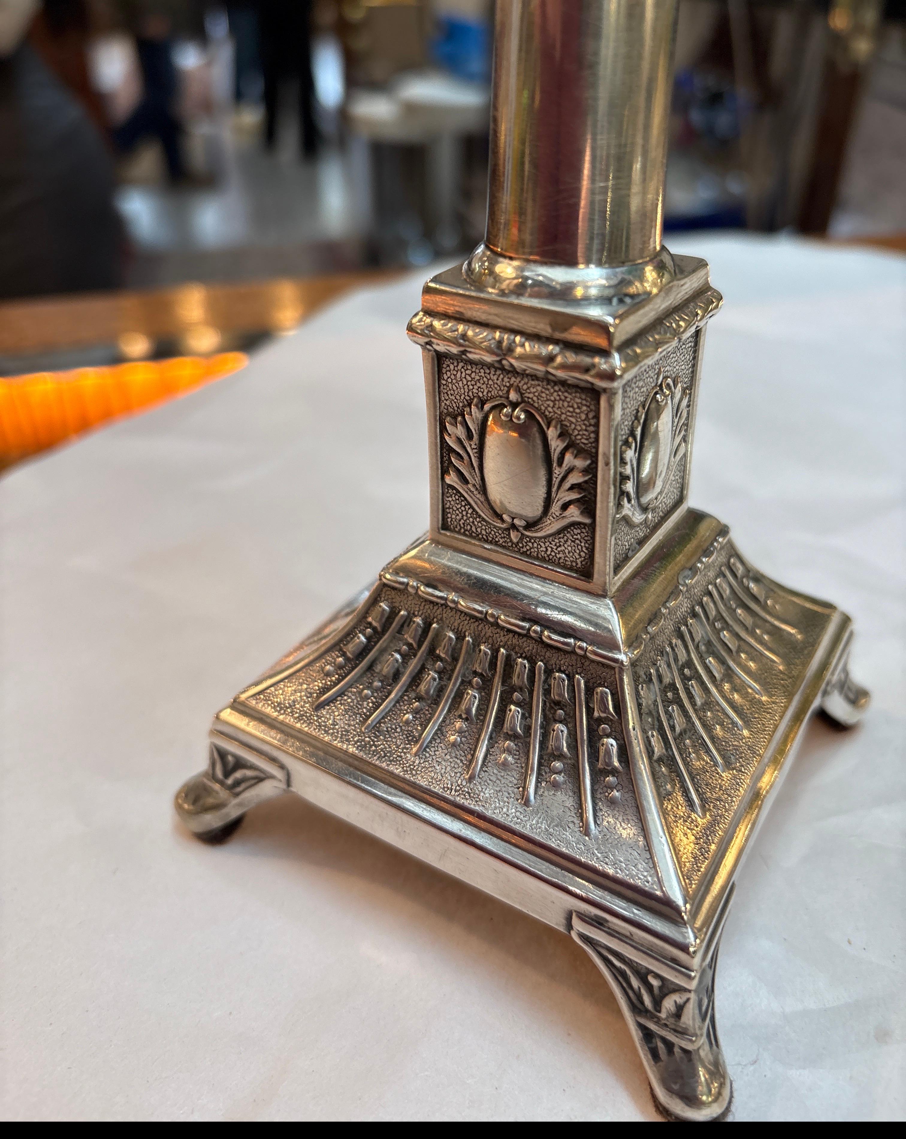 Coppia di candelieri a colonna in argento sterling del XIX secolo.  I piani con bobeches originali, sui piani di forma corinzia.  Le colonne centrali si assottigliano verso le basi a pianta quadrata.  I marchi sul bordo inferiore.  Sono tutti in