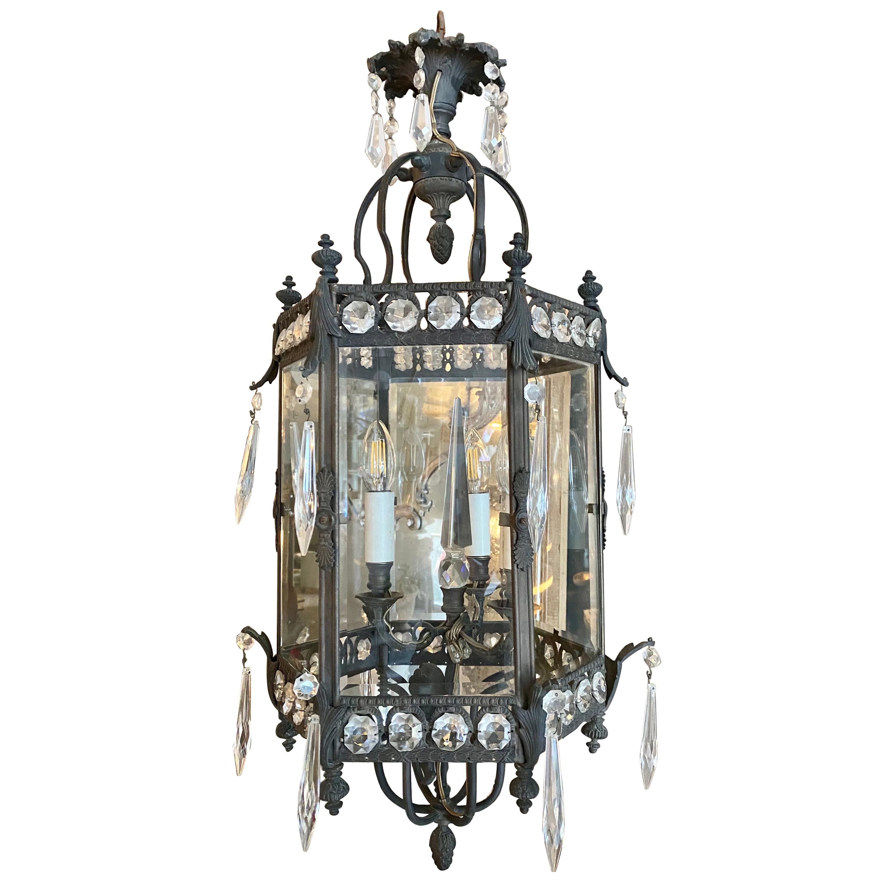 A pair of 19th century French lanterns in bronze with glass adornments and interior crystal prism. The panelled glass hexagon shaped frame decorated with acorns and foliage embellishments. Dressed with glass drops. The interior light branch is
