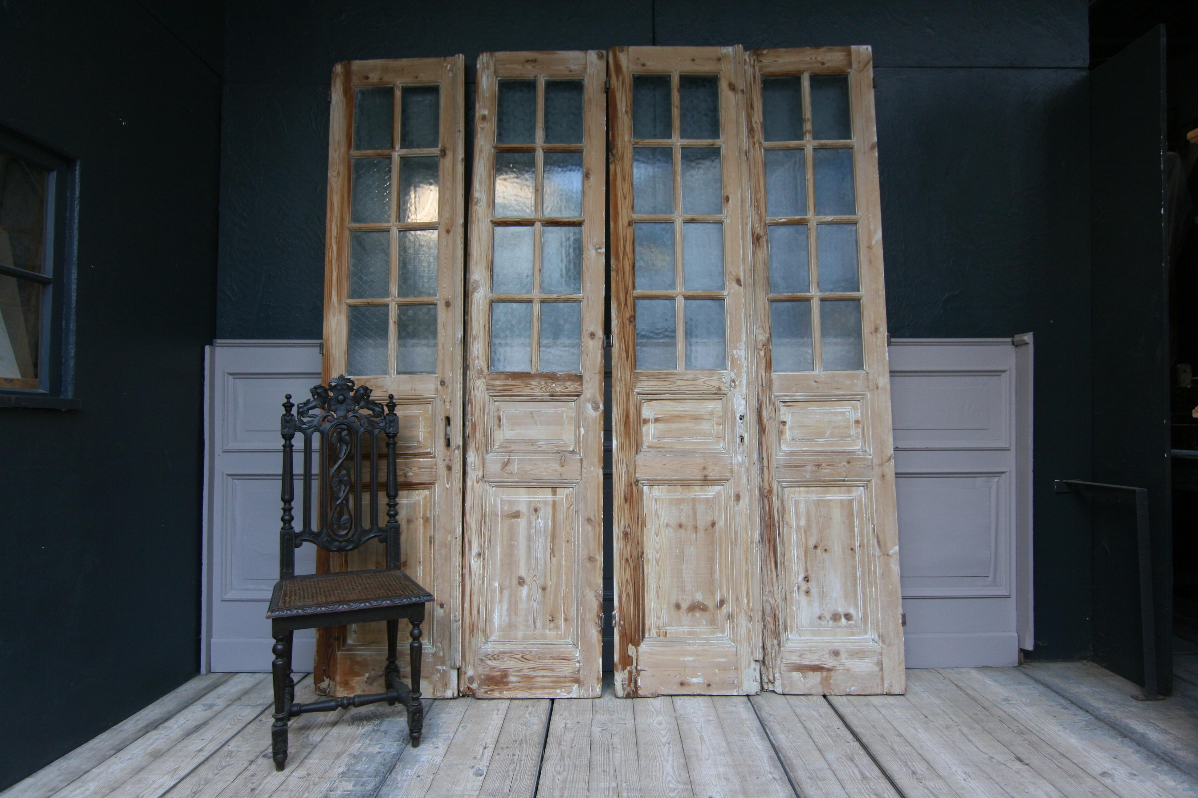 A pair of late 19th century French double doors made of pine. (Set of 4 doors.)
Each door is one half with glass and one half with 2 wood panels. 
The doors are in unrestored condition.

Perfect for being used as beautiful country house sliding