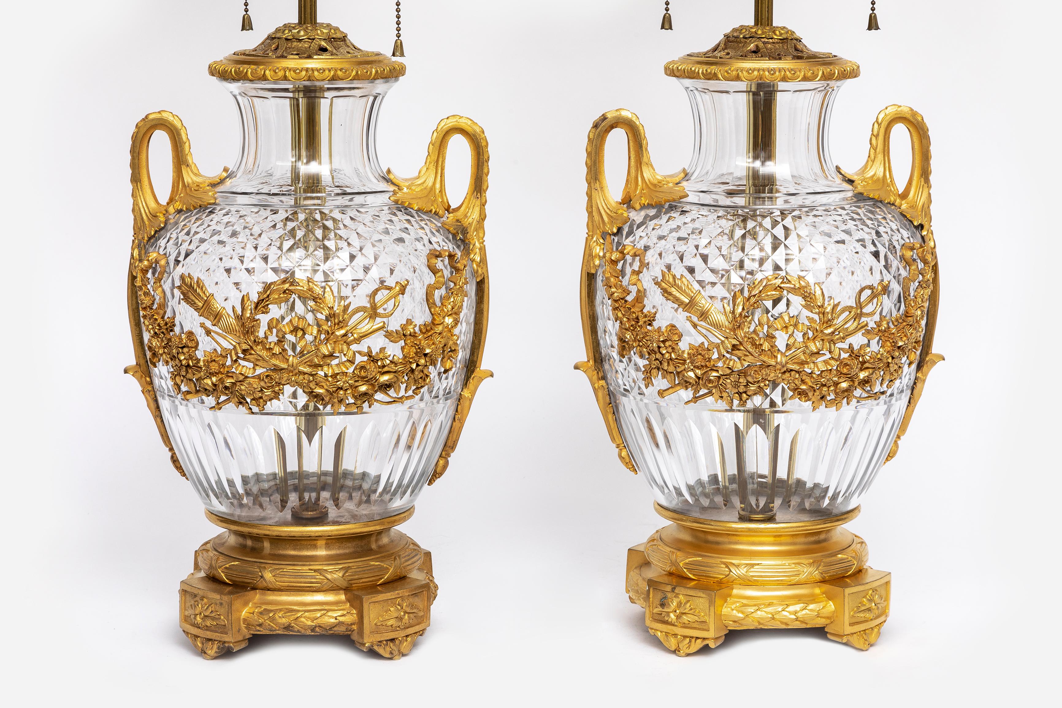 A Large Pair of 19th Century French Ormolu Mounted Hand-Diamond Cut Crystal Vases Turned-to-Lamps.  Each lamp features hand-diamond cut crystal bodies with a prismatic lattice pattern that catches and refracts light. The crystal is meticulously