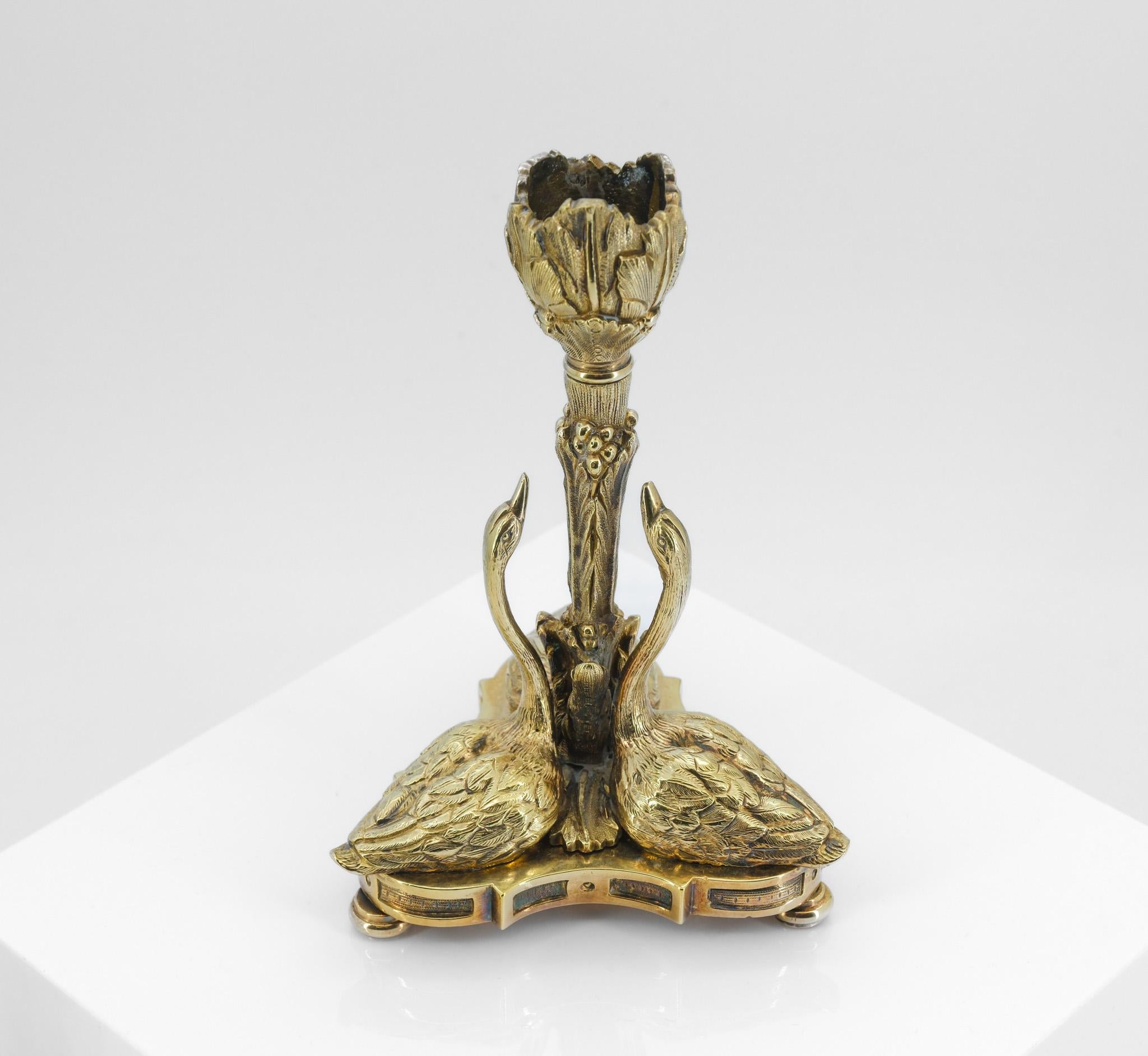 Pair of 19th century gilt bronze candlesticks having cast sconces, with the foliate stems surrounded by three swans on swept trefoil bases and bun feet.

The candlesticks are after a design by William Bateman II for Rundell, Bridge and Rundell.