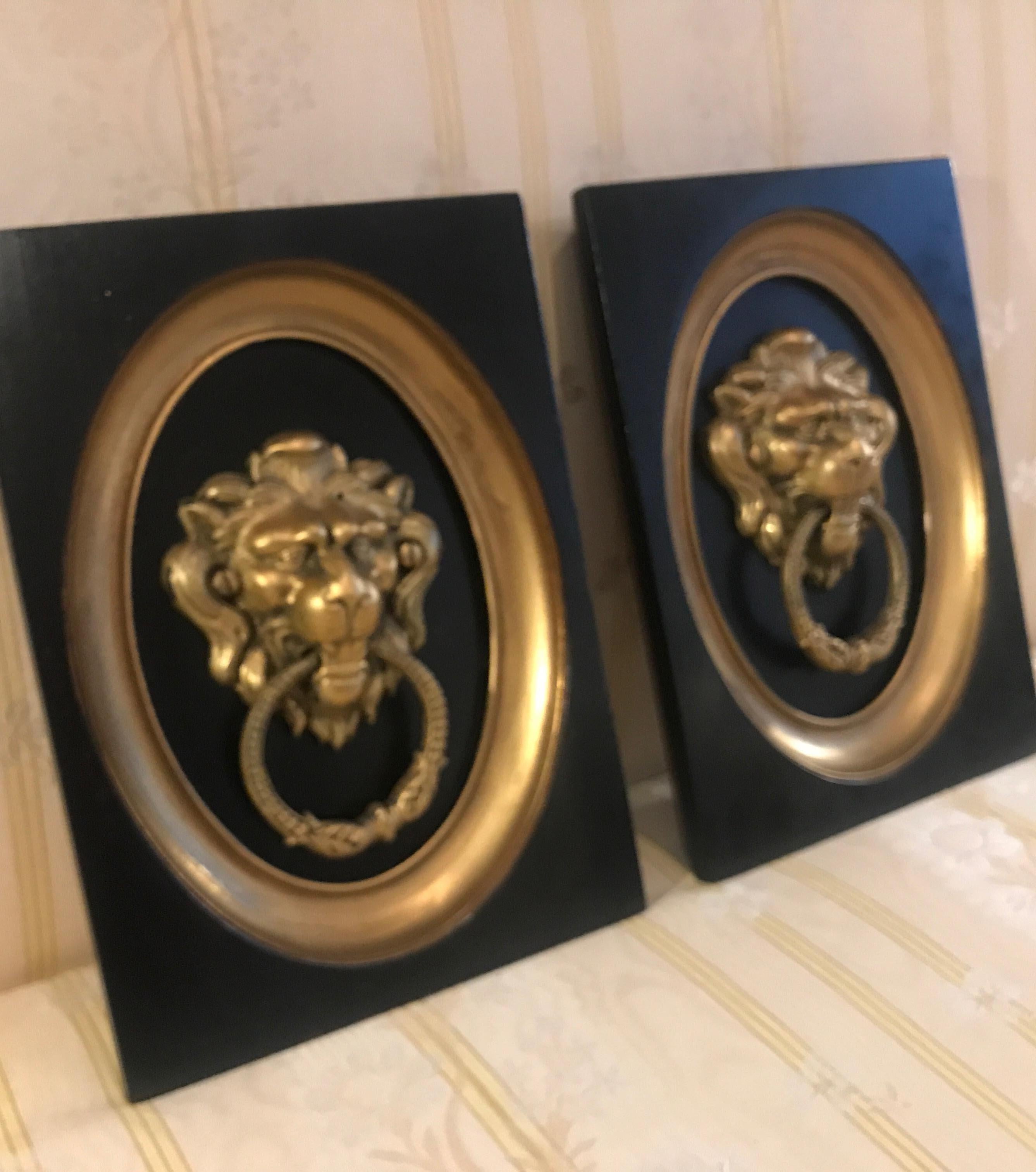 A pair of 19th century cast gilt bronze lion door knockers mounted and framed. The gilt bronze lions with rings mounted on a black backing with an ebonized and gilt frame.