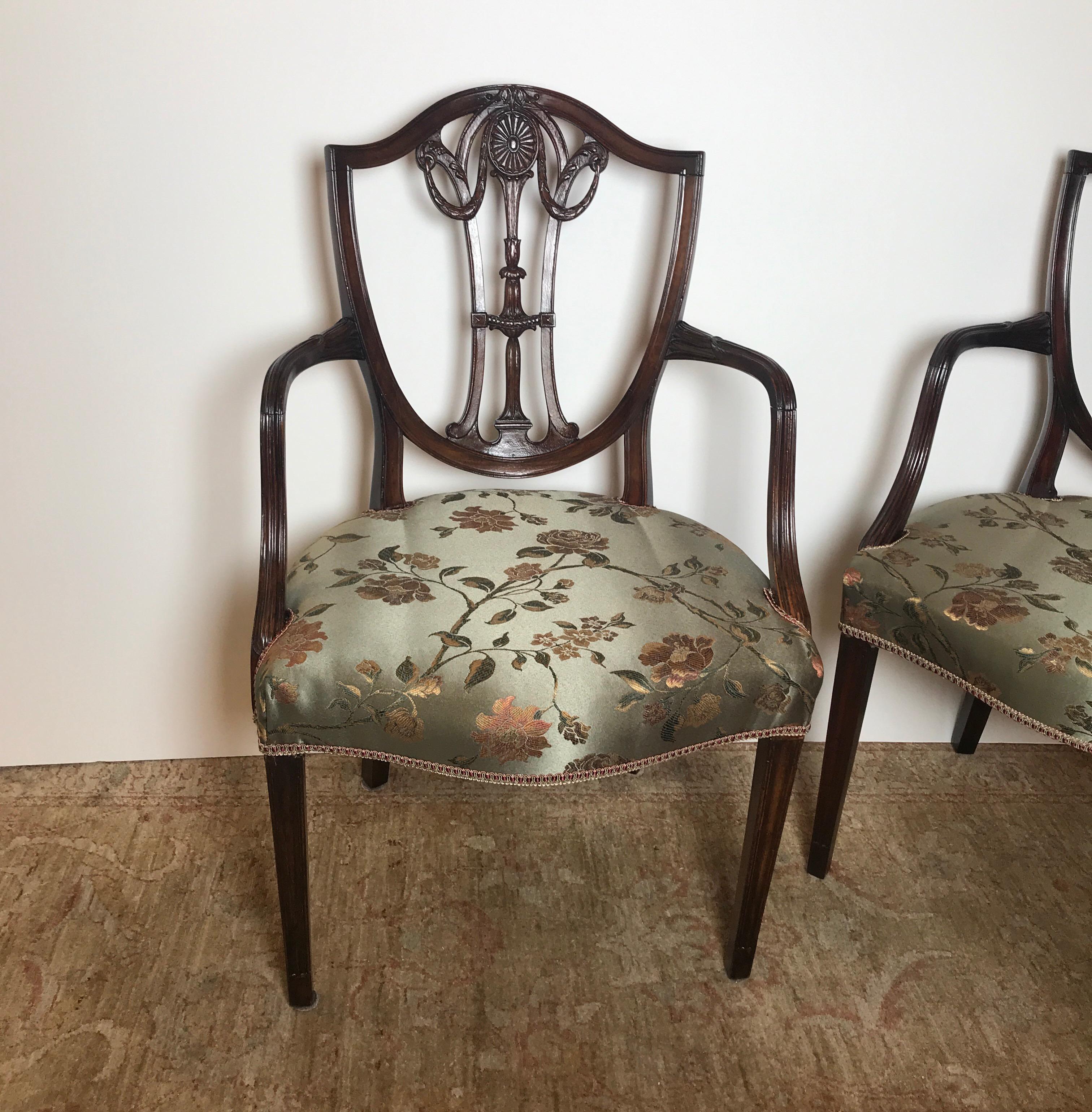 A pair of hand carved mahogany armchairs, England, circa 1875. The chairs with delicately carved shield backs also carved along the arms with recent Lampas fabric. Classic graceful lines and graceful style.