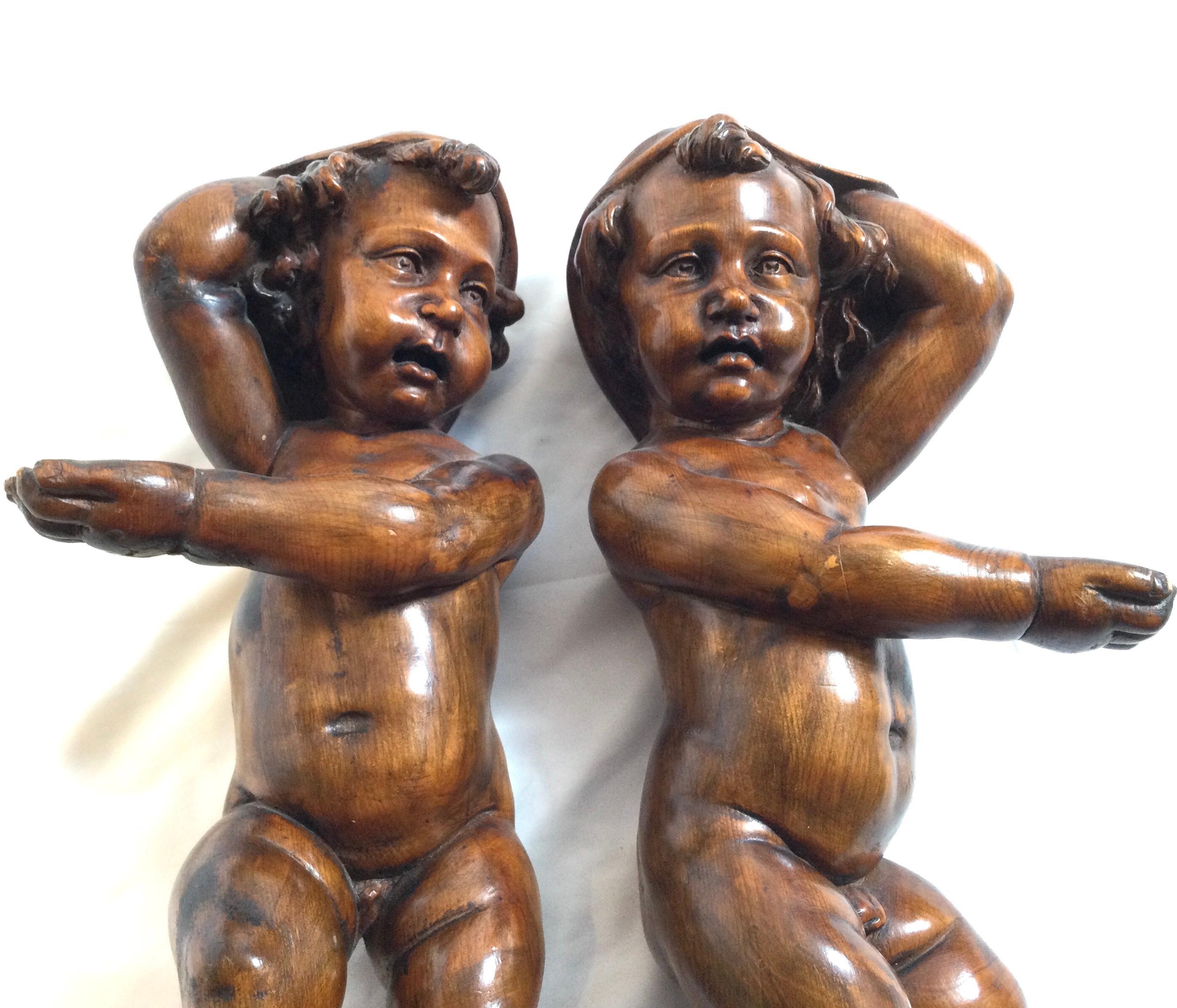 A pair of caved walnut 19th century Italian cherubs with an original warm finish. These were apparently taken from a large piece of furniture or elaborate wood paneled room. Mostly intact with the big toe on each missing.