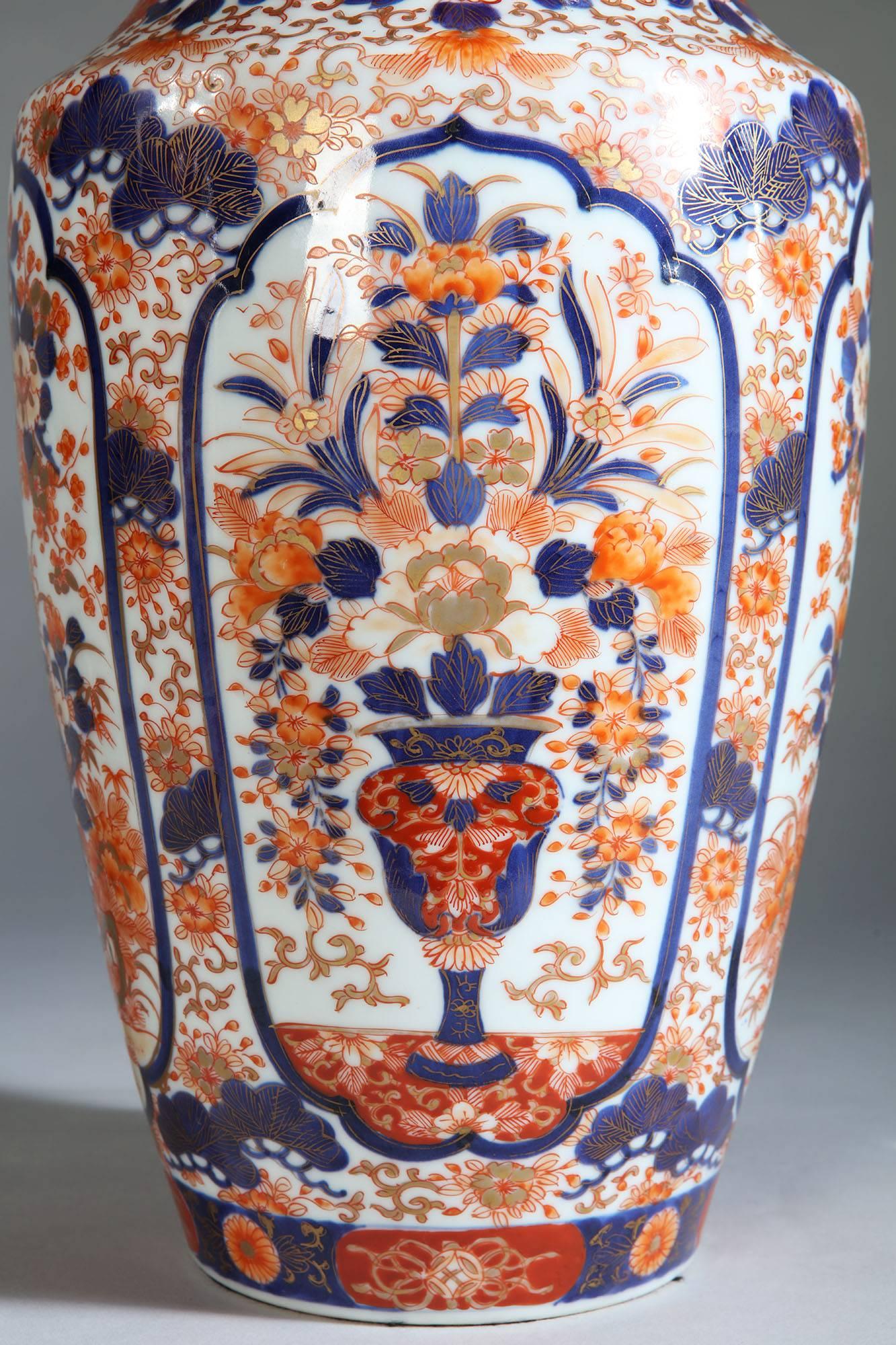 A pair of mid-19th century Imari vases, showing four cartouches filled with floral displays and exotic trees, now converted as lamps.