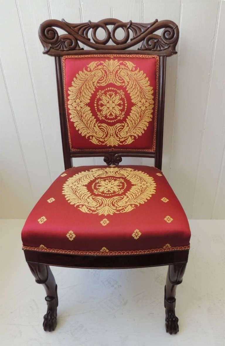 This wonderful pair of side chairs are made of mahogany with silk cushions. The cushions feature a central wreath with floral and foliage decoration. The ears of the chair feature beautiful scrolls and rounded tulip stems. The solid spat has a base