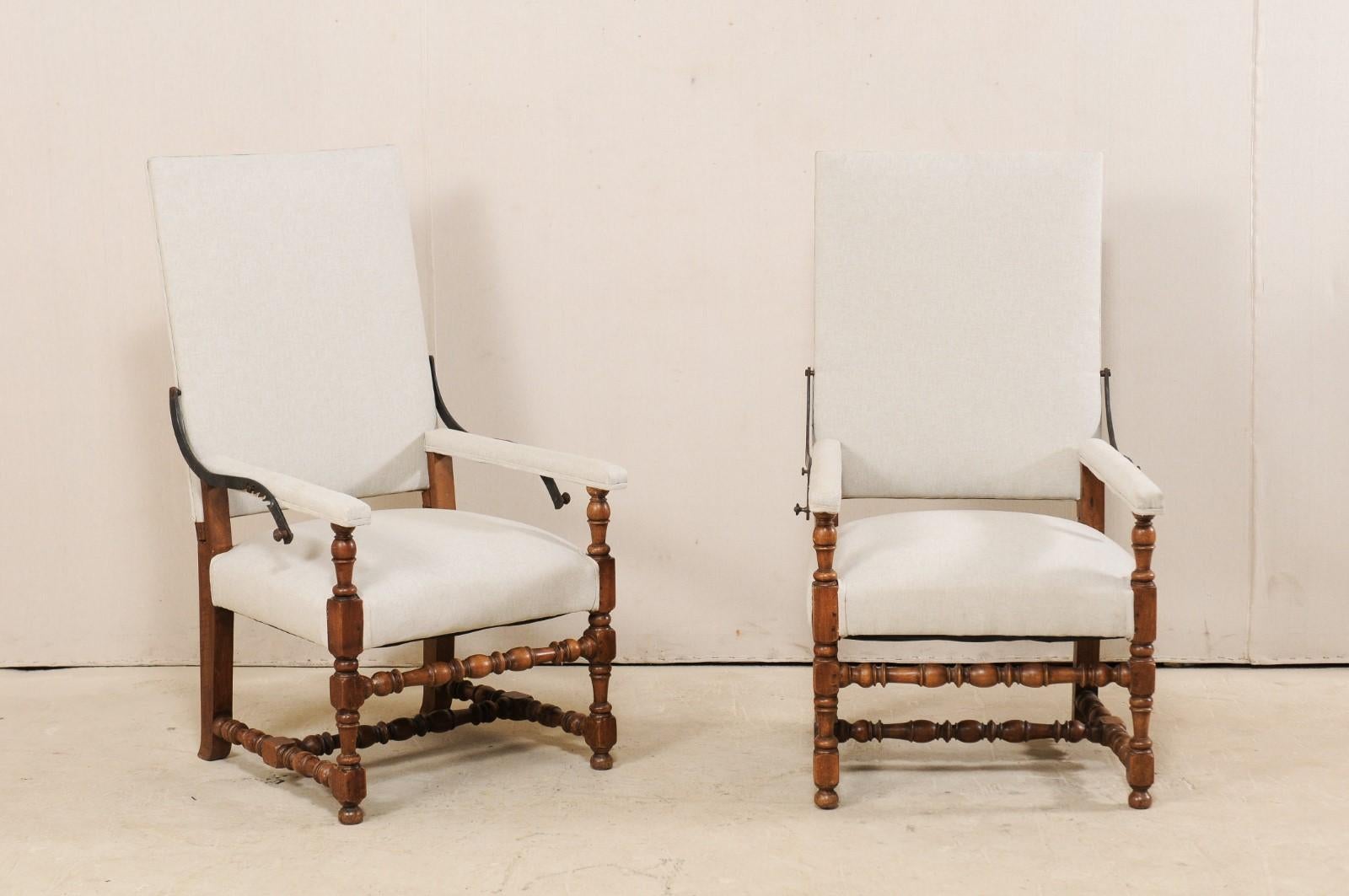 A pair of Italian reclining carved wood and upholstered armchairs from the 19th century. These unique antique chairs from Italy, designed in Louis XIII style, feature cleanly designed backs with flat top rails and straight arms. The
