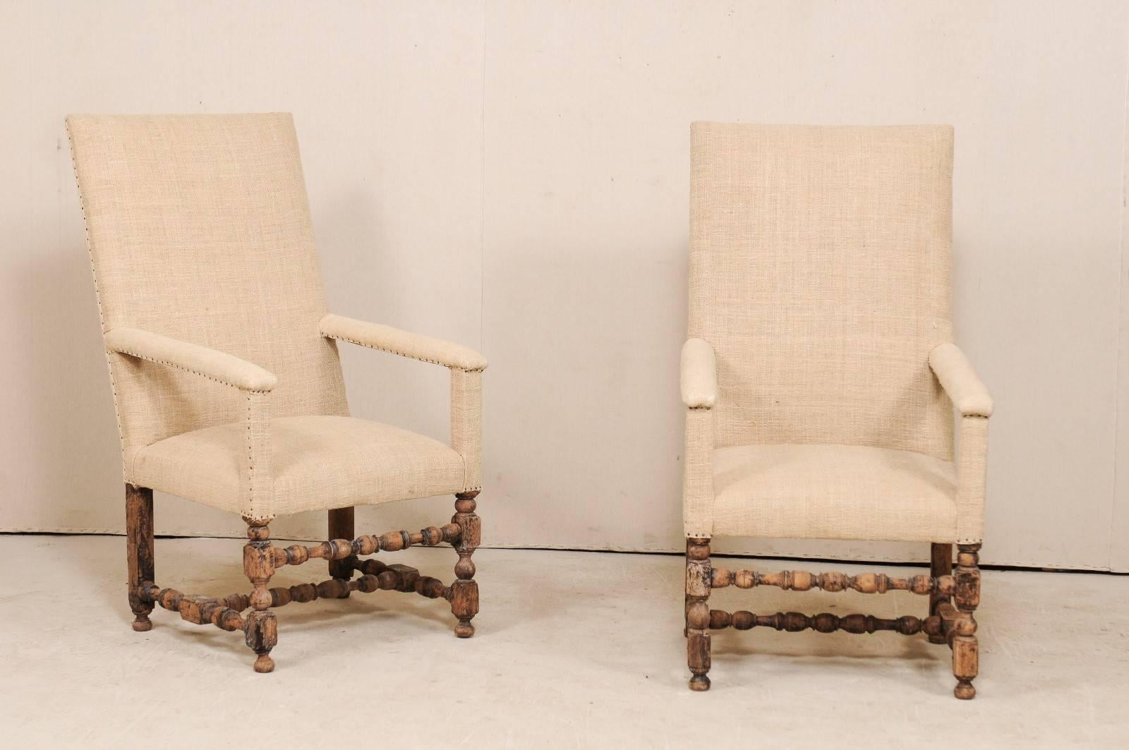 A pair of Italian 19th century upholstered and carved wood arm chairs. This pair of antique Italian armchairs feature tall, rectangular backs with squared crest rail, and nicely turned wood legs. The straight lines are repeated within the arm rest