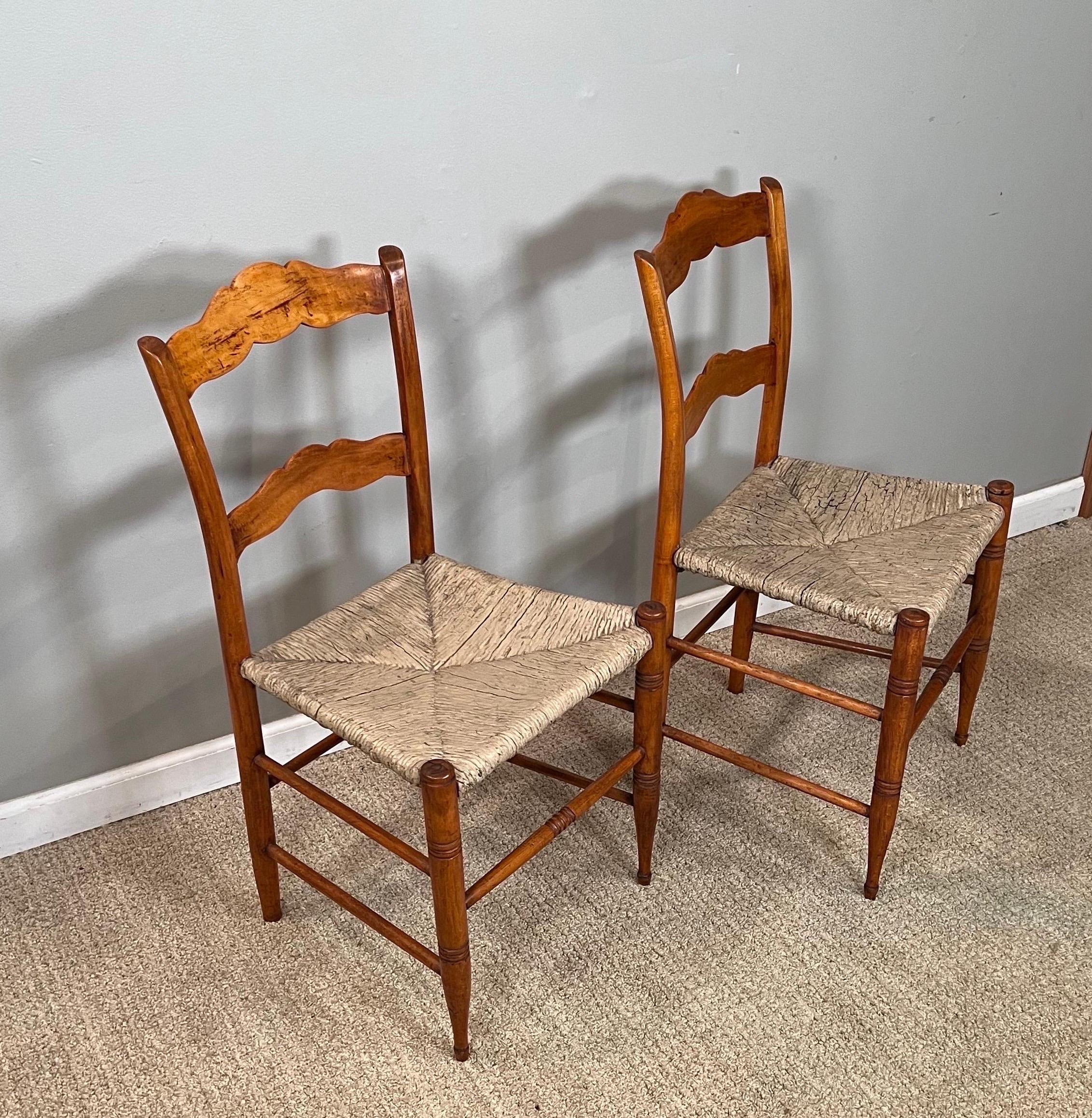 A pair of 19th century maple side chairs with rush seats. 
Seats with remnants of paint. Frames tightened. Chairs touched up & polished.