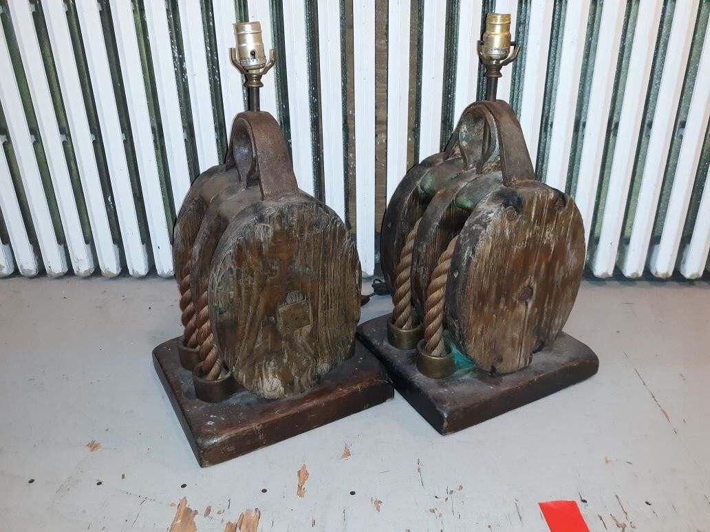 Very unique pair of old 19th century nautical ship pullies now as lamps. The original weathers and oxidized finish with a natural distressing. The custom bases added. Made of wood, iron and rope. These are rather heavy, around 50 pounds each.