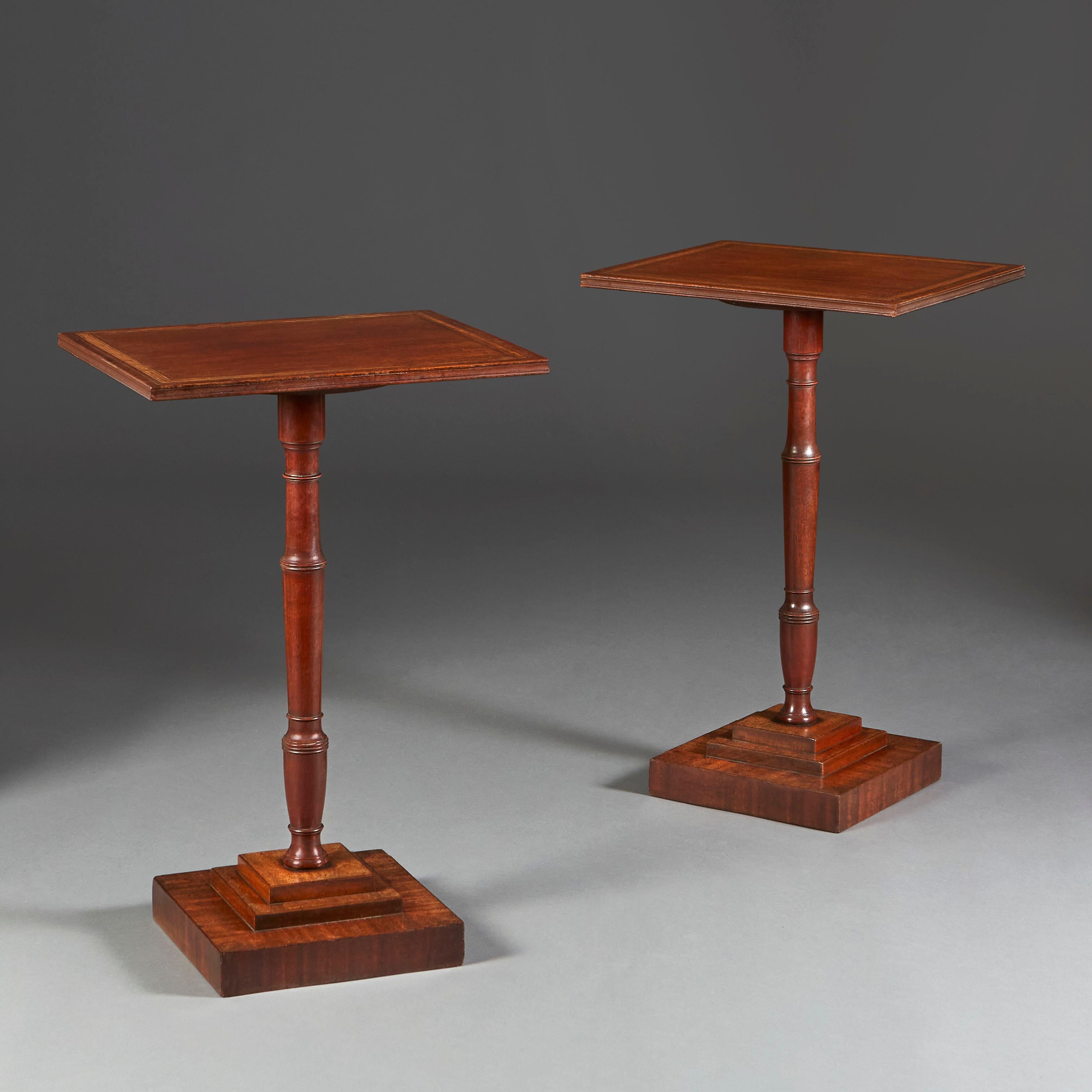 An unusual pair of mid 19th century mahogany occasional tables, crossbanded with tulipwood, supported on turned pedestals and stepped, tiered bases.