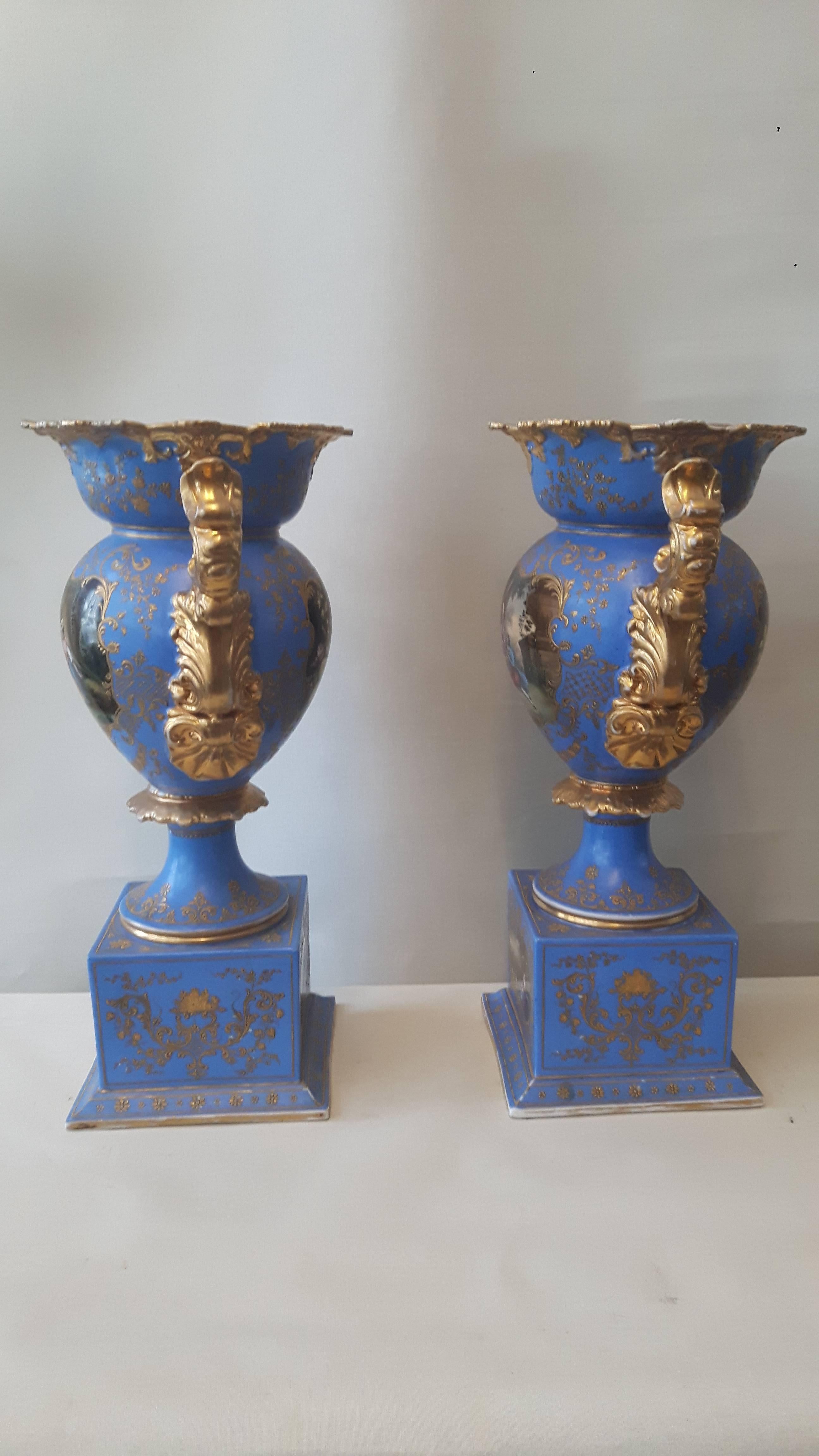 Coppia di vasi da caminetto di Napoleone III in stile settecentesco, elaborati e dorati su uno sfondo :bleu de ciel. Ogni vaso è decorato con due pannelli, uno con eleganti bouquet di fiori e l'altro con scene d'amore rurale in stile Watteau.
I