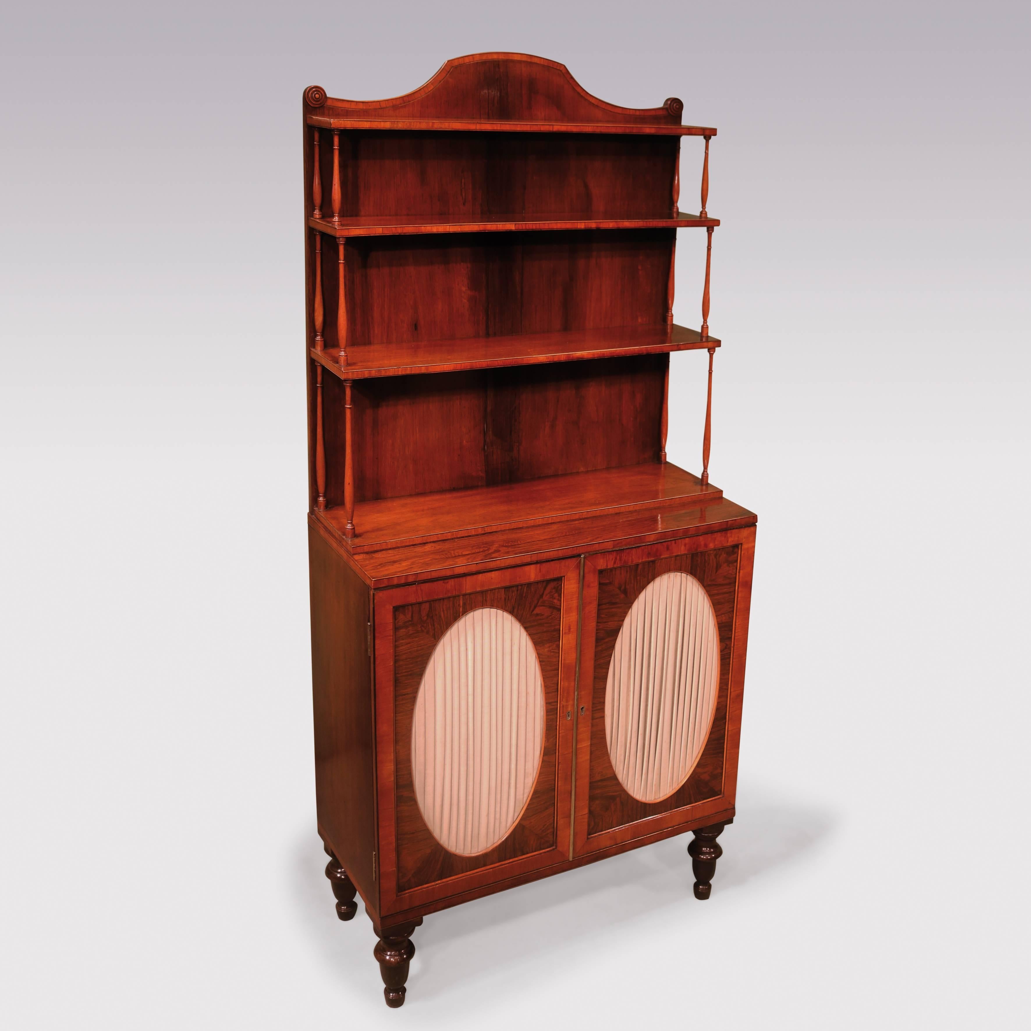A fine quality pair of early 19th century Regency period rosewood 2-door cabinets, boxwood and ebony strung throughout, with satinwood banded and spindle turned upper parts having shaped tops flanked by roundels. The cabinets differing in width by 4