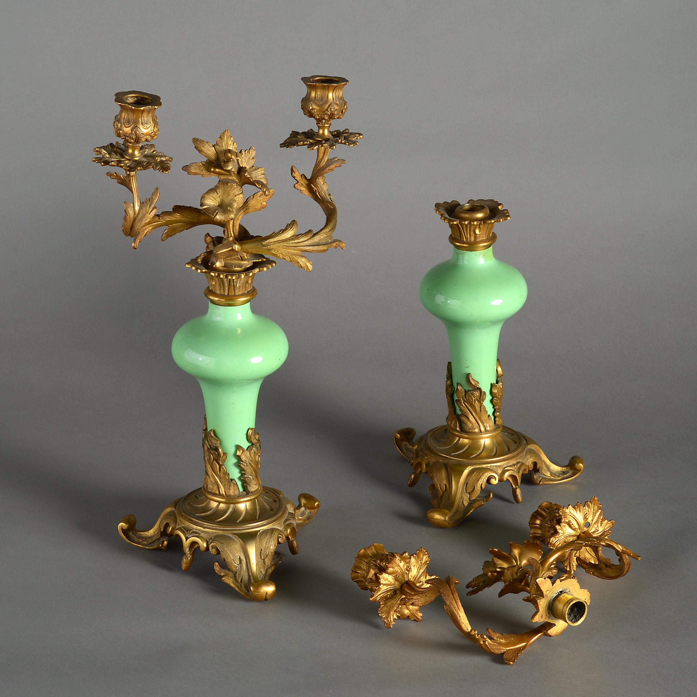 A pair of mid-19th century Rococo Revival ormolu and porcelain candelabra with foliate scrolling arms to green porcelain on a base of the same. 

Condition; both porcelain bases with minor repairs as shown in photographs.