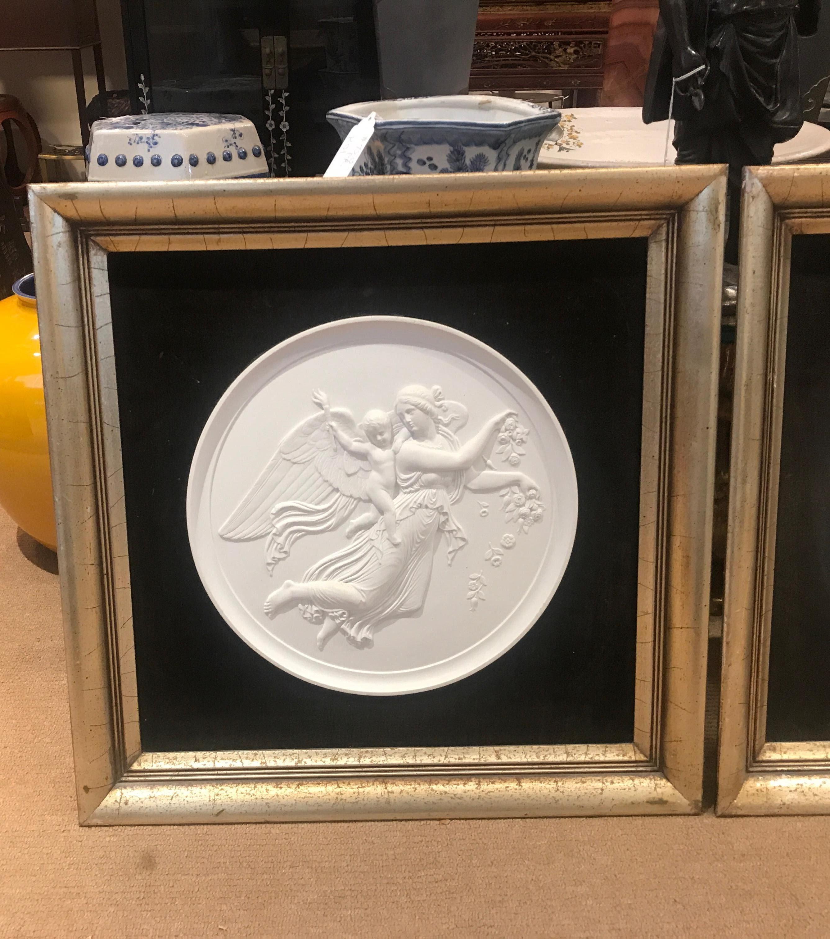 A large pair of antique Royal Copenhagen porcelain allegorical relief plaques with Smokey grey velvet mats. The frames are a silver and gold tone gilt on wood with a distresses finish. They are 19th century plaques framed in the early part of the