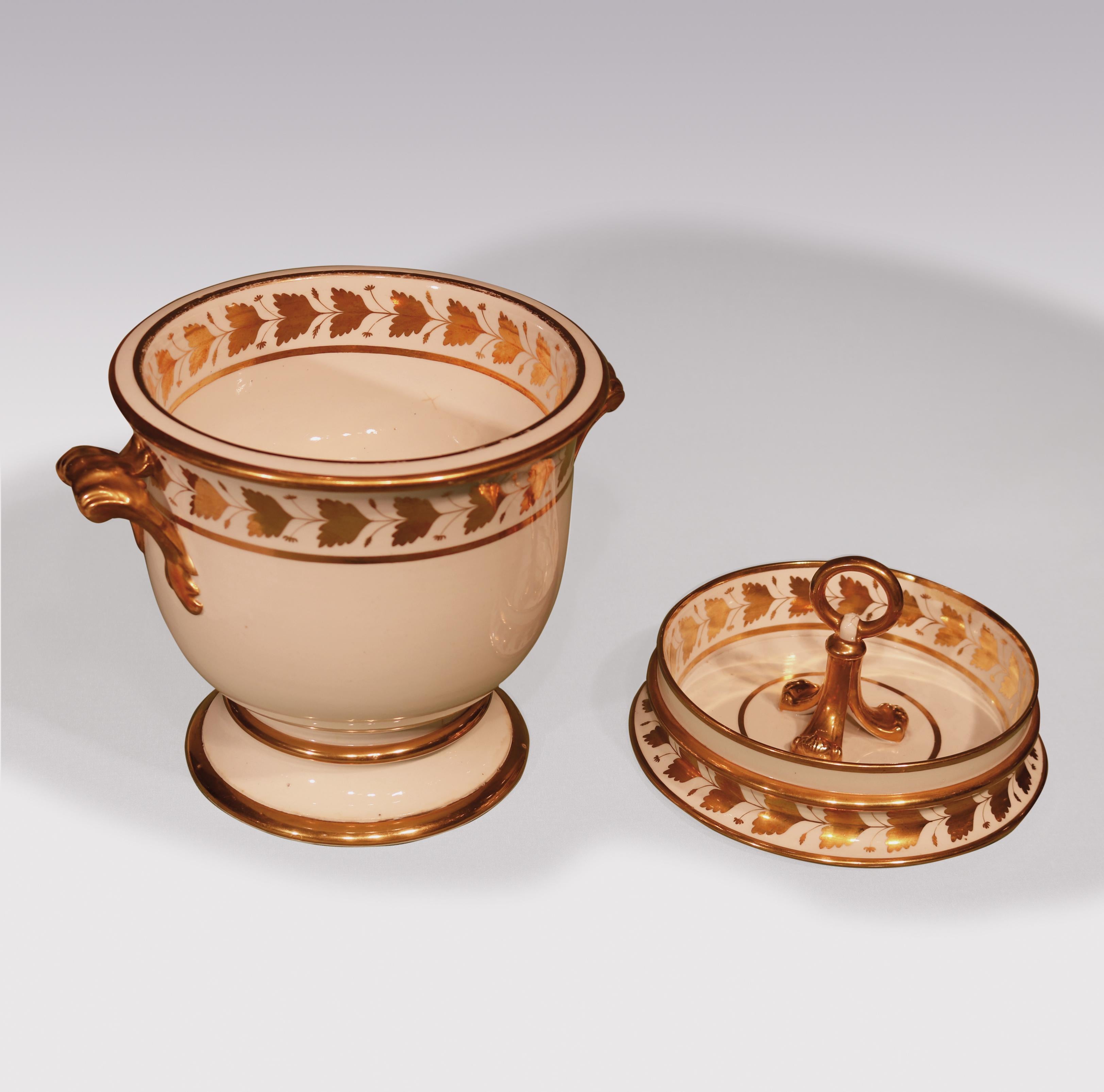 An early 19th century pair of porcelain ice-pails with gilt leaf decorated borders, part of a dessert service, comprising 20 plates, 3 shell dishes, 3 circular dishes, 4 oval dishes, 1 comport and a pair of ice-pails.