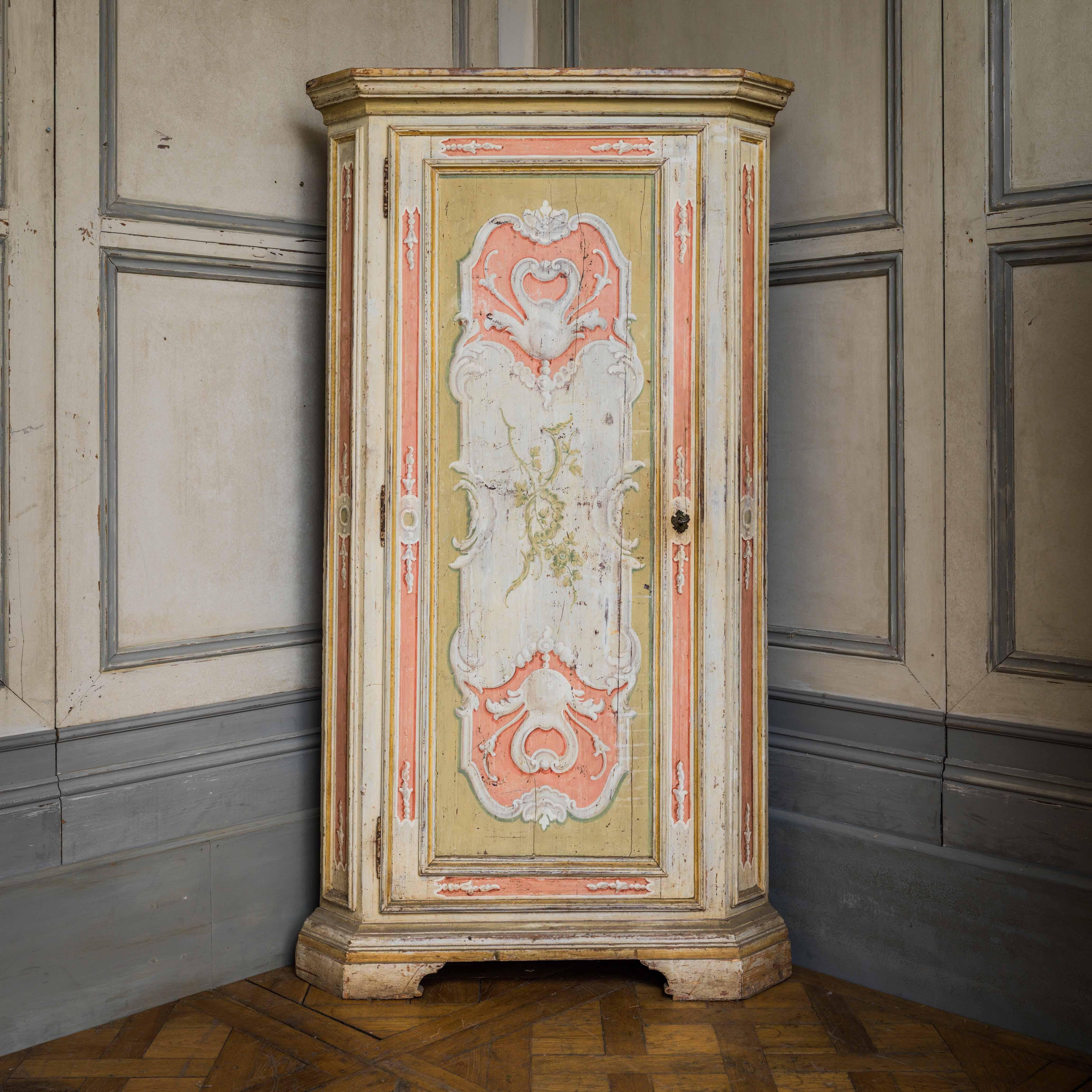 A pair of Italian, 19th century corner cabinets, hand painted in a lyrical Rococo style with a lively palette of pink, stone green and white highlights. The surprise inside, is that the pieces have been fully lined in a vintage floral paper of