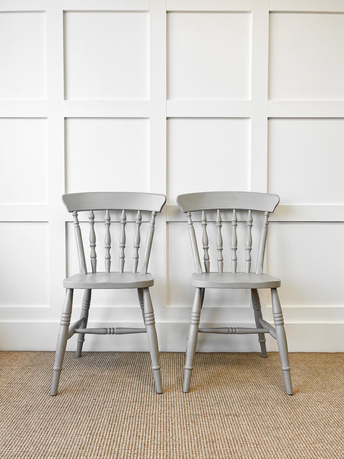 A good pair of vintage ash spindle back side chairs. Painted French grey and very solidly built in the traditional way.  Handsome profiles and good and heavy.  Perfect around a farmhouse table! Solid in joint. These are not antiques.

Condition: