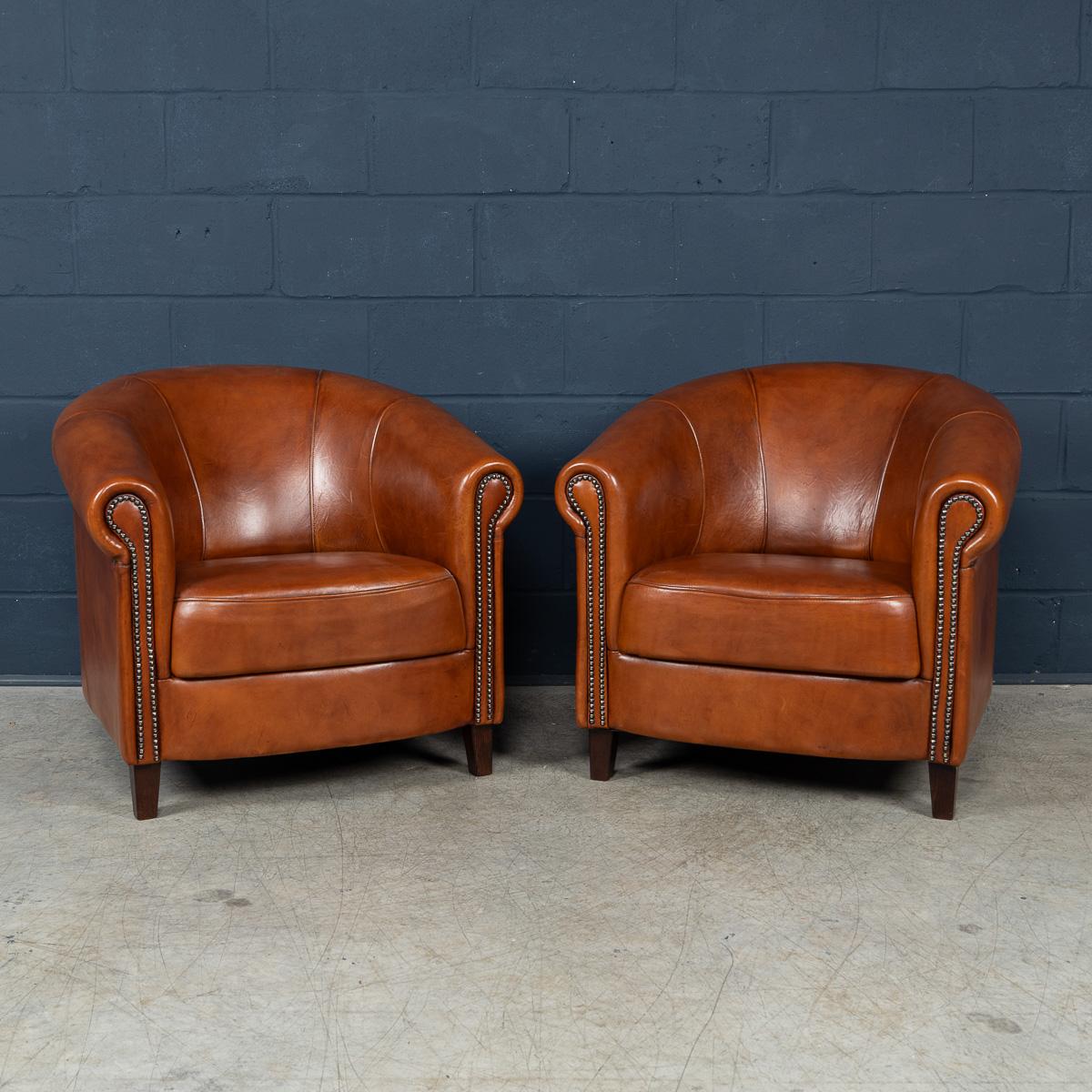 Showing superb patina and colour, this wonderful pair of club chairs were hand upholstered sheepskin leather in Holland by the finest craftsmen in the latter part of the 20th century.

The design and craftsmanship of sheep leather furniture was