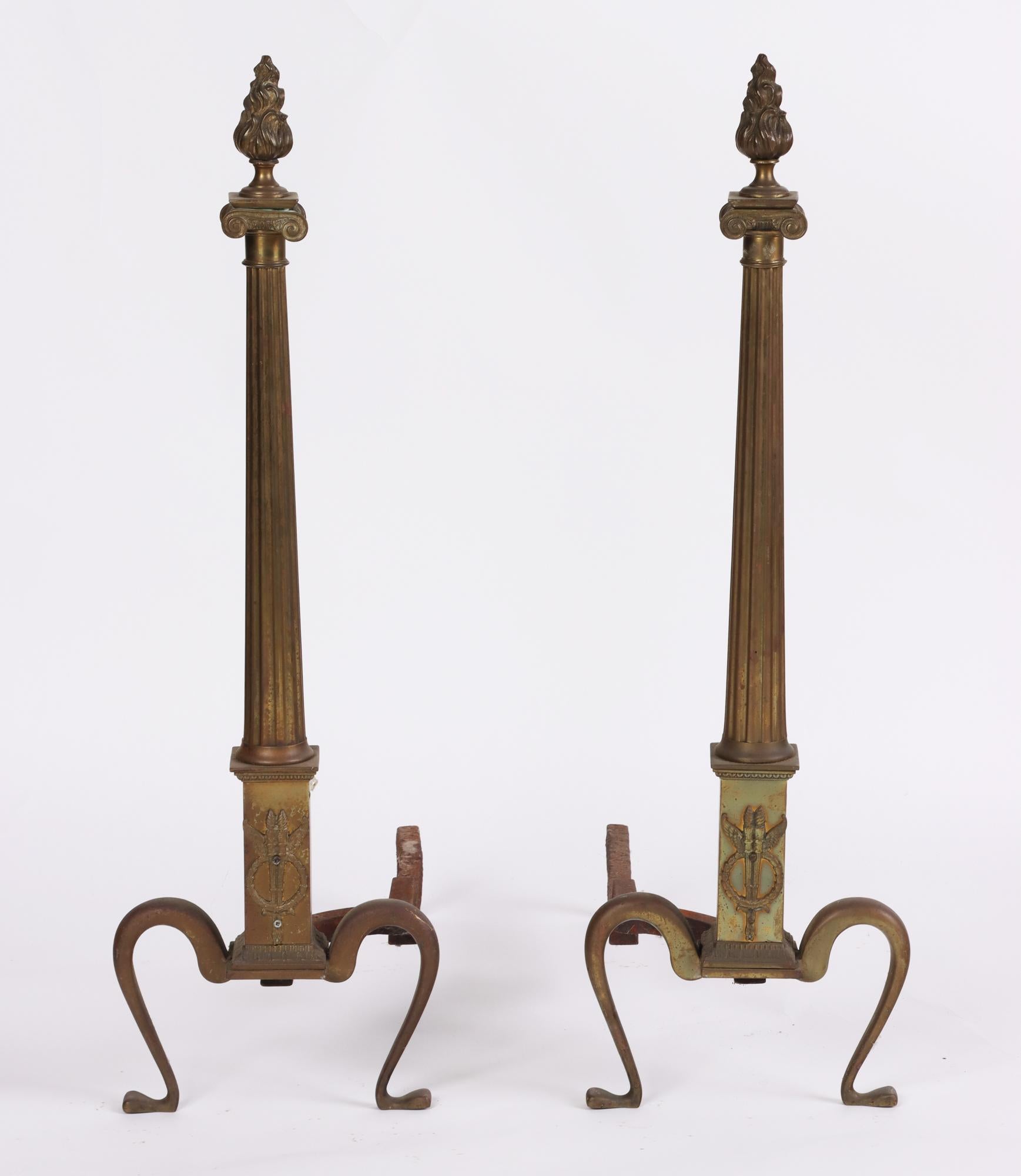 A pair of early 20th century Neoclassical brass Andirons with flame finials and column shaft and overly curved legs.