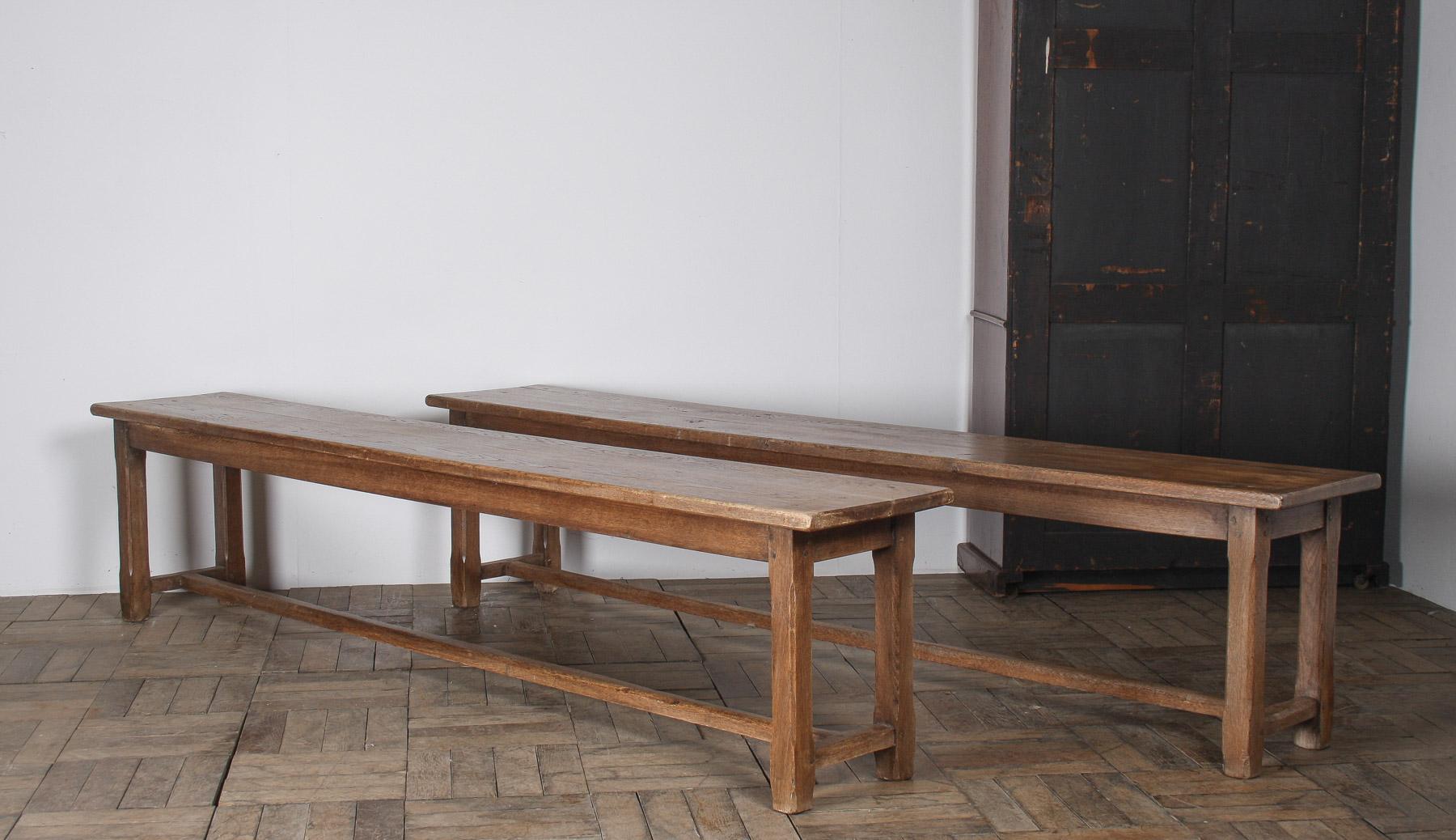 Superbe paire de bancs anciens en chêne français de 2 m de long, vers 1920, qui témoignent d'un savoir-faire exceptionnel et d'un design intemporel. Cette paire assortie est fabriquée en chêne massif, mettant en valeur la beauté et la durabilité du