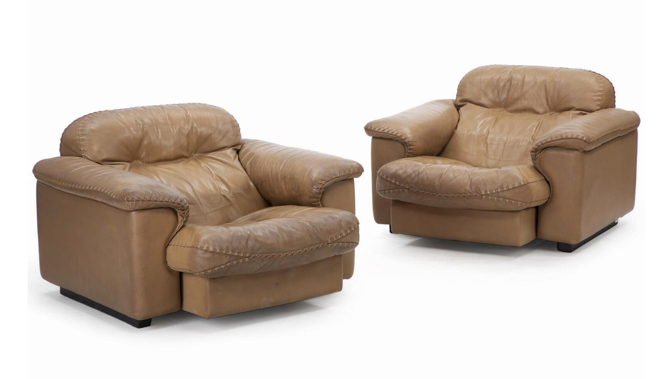 Una coppia di poltrone con gambe in legno laccato nero. Seduta, lati e schienale rivestiti in pelle marrone. Modello DS 101 (noto anche per il film di James Bond 