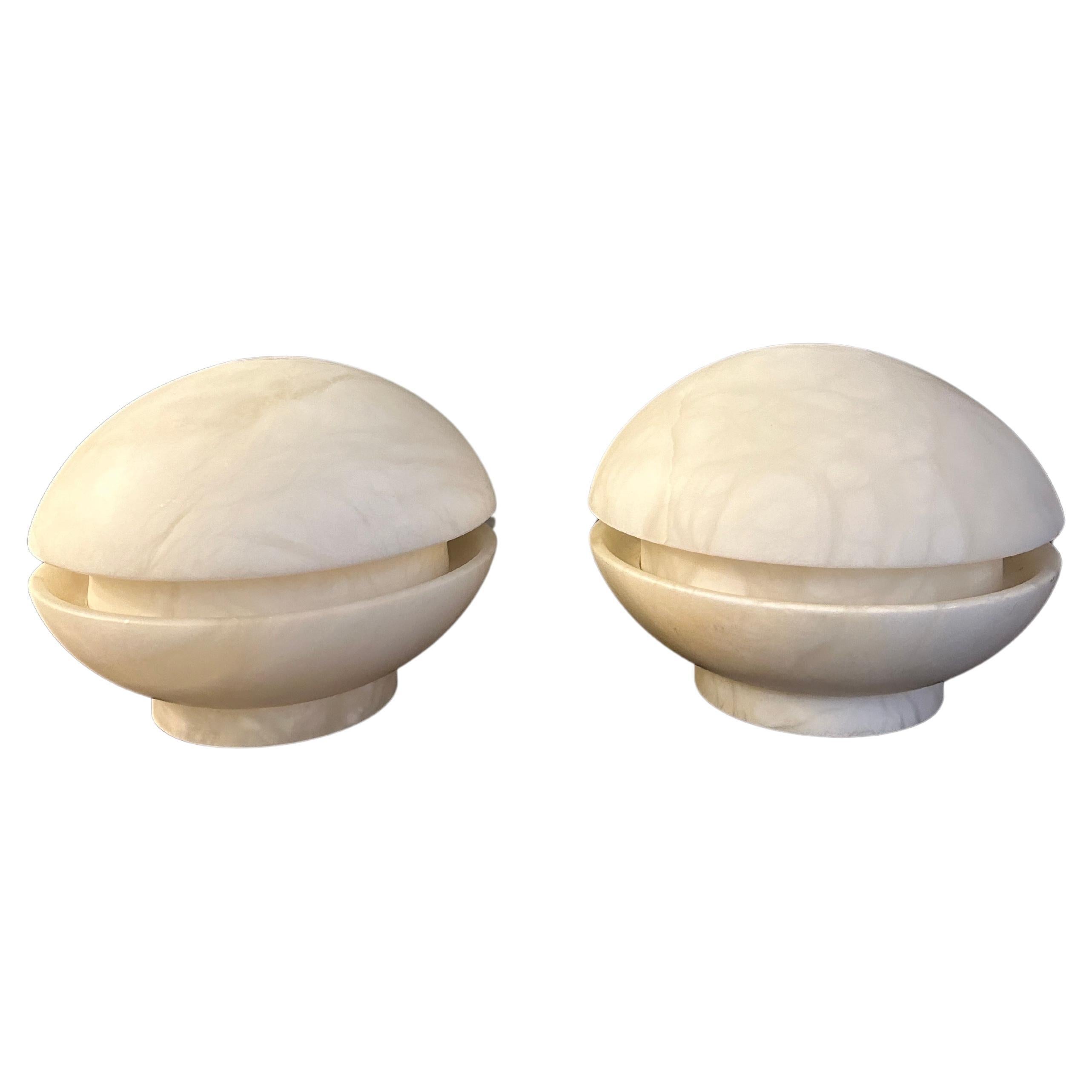 A pair of almost UFO shaped Alabaster table lamps, very Mid Century in style. White alabaster with gentle veining. As shown in images with two different shades of light given when using an opaque bulb then a clear bulb so quite versatile in light