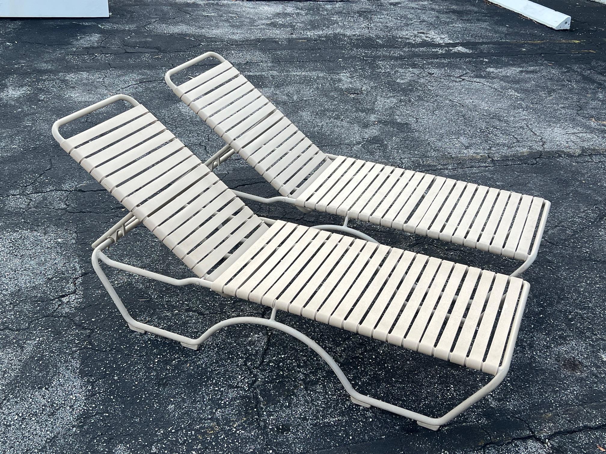 Un par de chaises longues de aluminio con recubrimiento de polvo de Tropitone con respaldos ajustables, que incluyen cojines Gold Crest. 