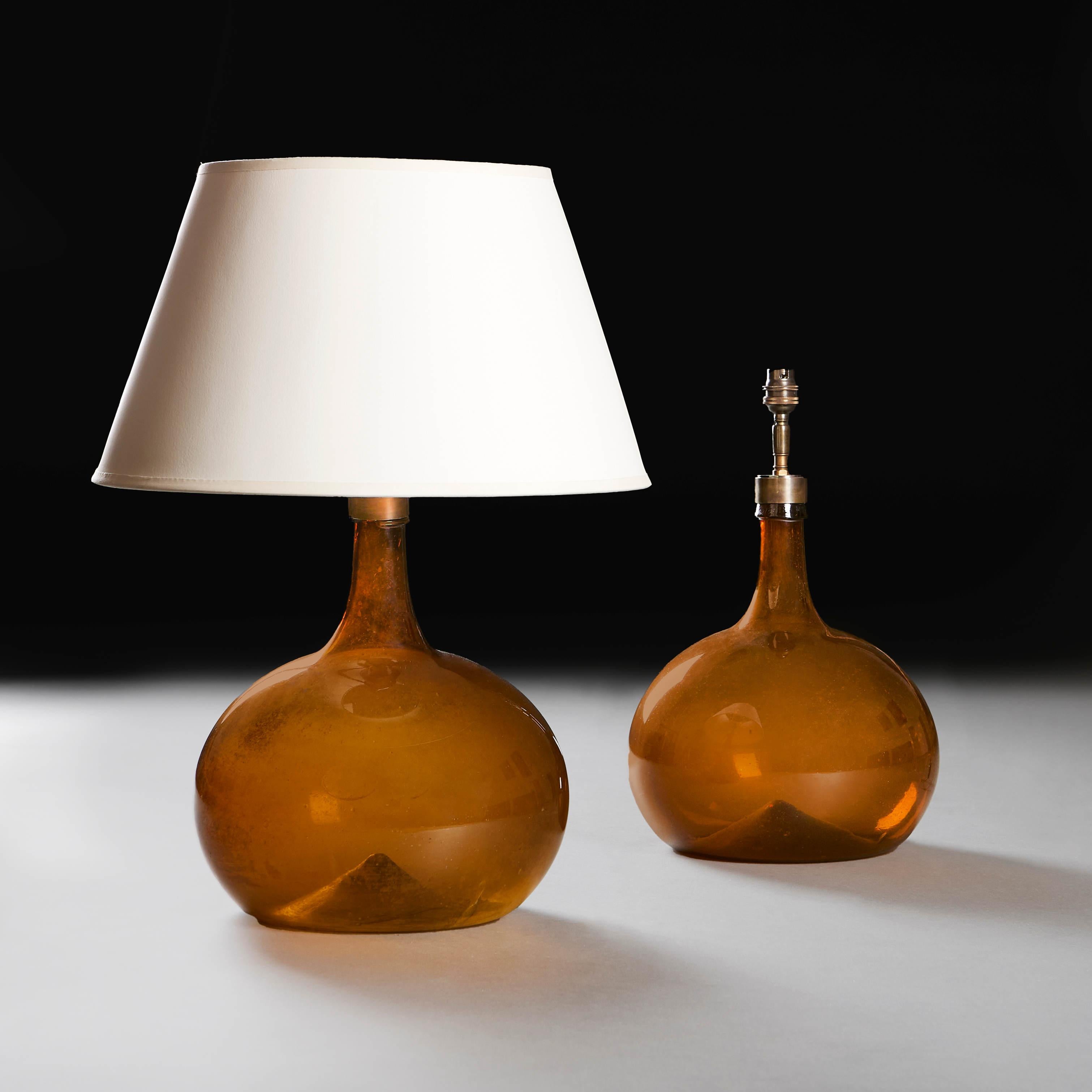 A pair of amber glass wine vessels of rotund form with bottle necks, now converted as lamps
France, circa 1900
Height of vase 33.00cm
Height with shade 58.00cm
Diameter of base 25.00cm
Please note: Does not include the lampshade. Photographed with