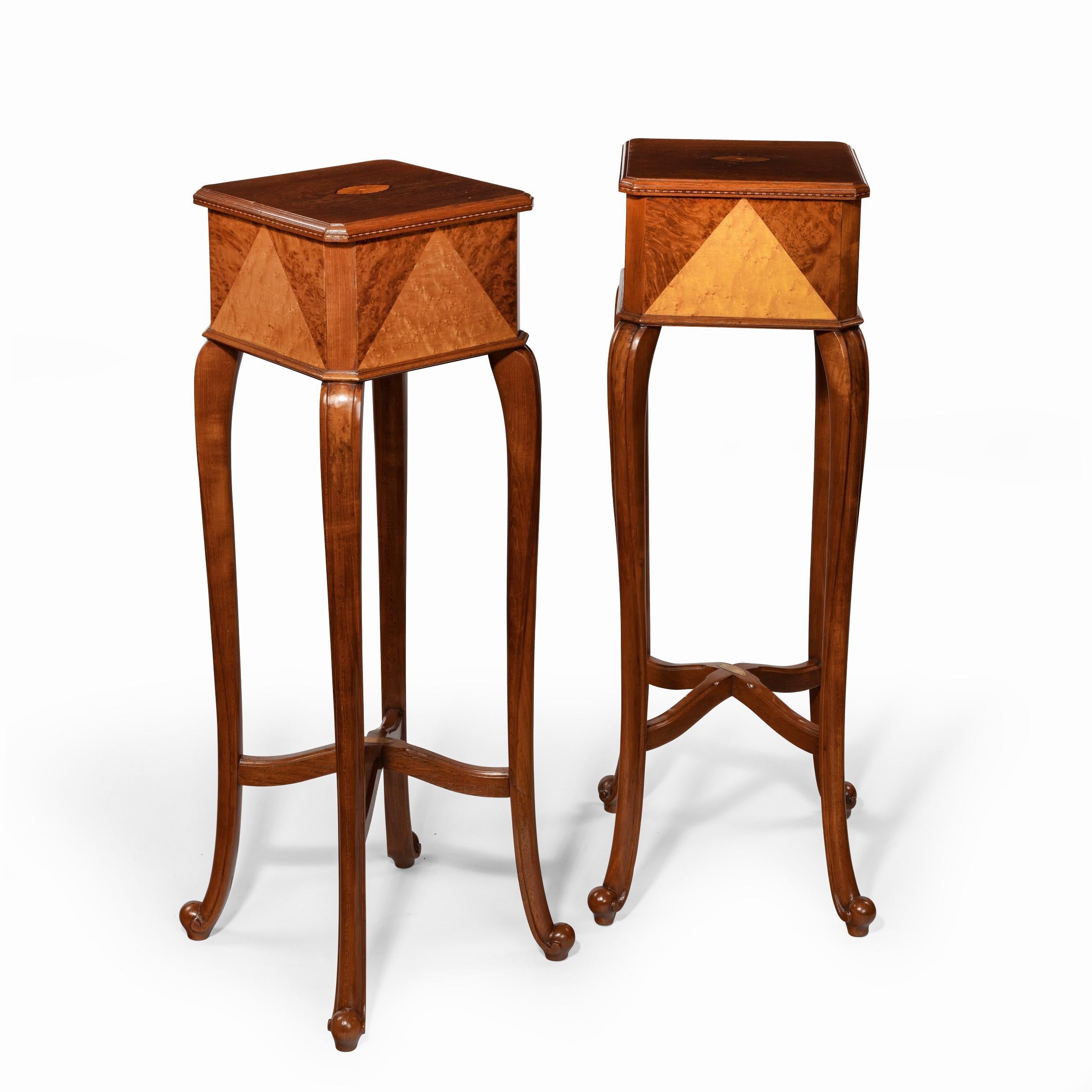 Une paire de stands en teck anglo-indien, chacun de forme carrée reposant sur quatre pieds cabriole, la décoration comprenant des triangles audacieux de bois exotiques contrastés, avec une plaque ovale en laiton indiquant 