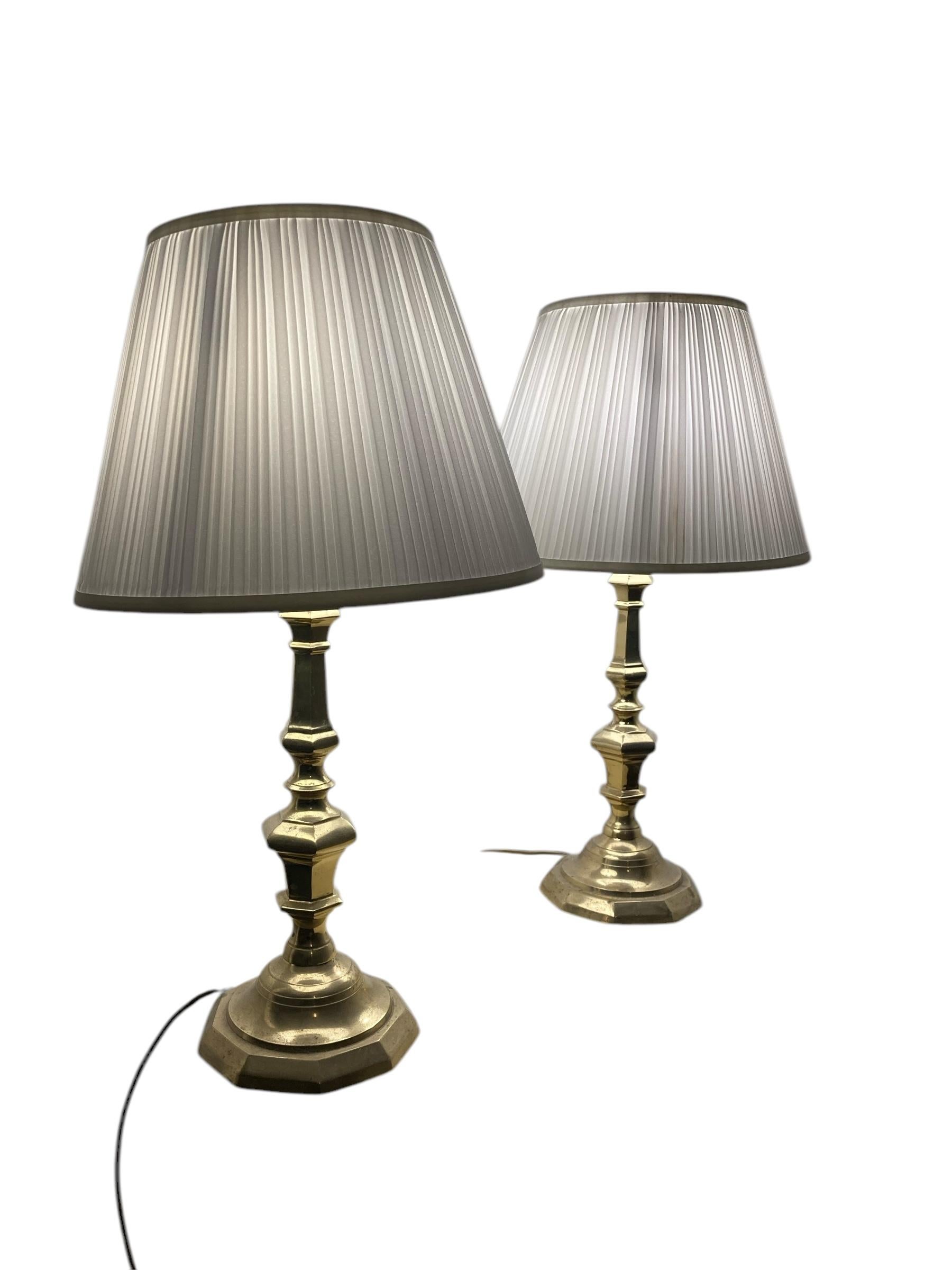 A Pair of Antique Brass bedside or Table Lamps white pleated shades. Designed to add a touch of elegance and sophistication to any room. Crafted from high-quality brass, these lamps feature a timeless finish that complements a variety of interior