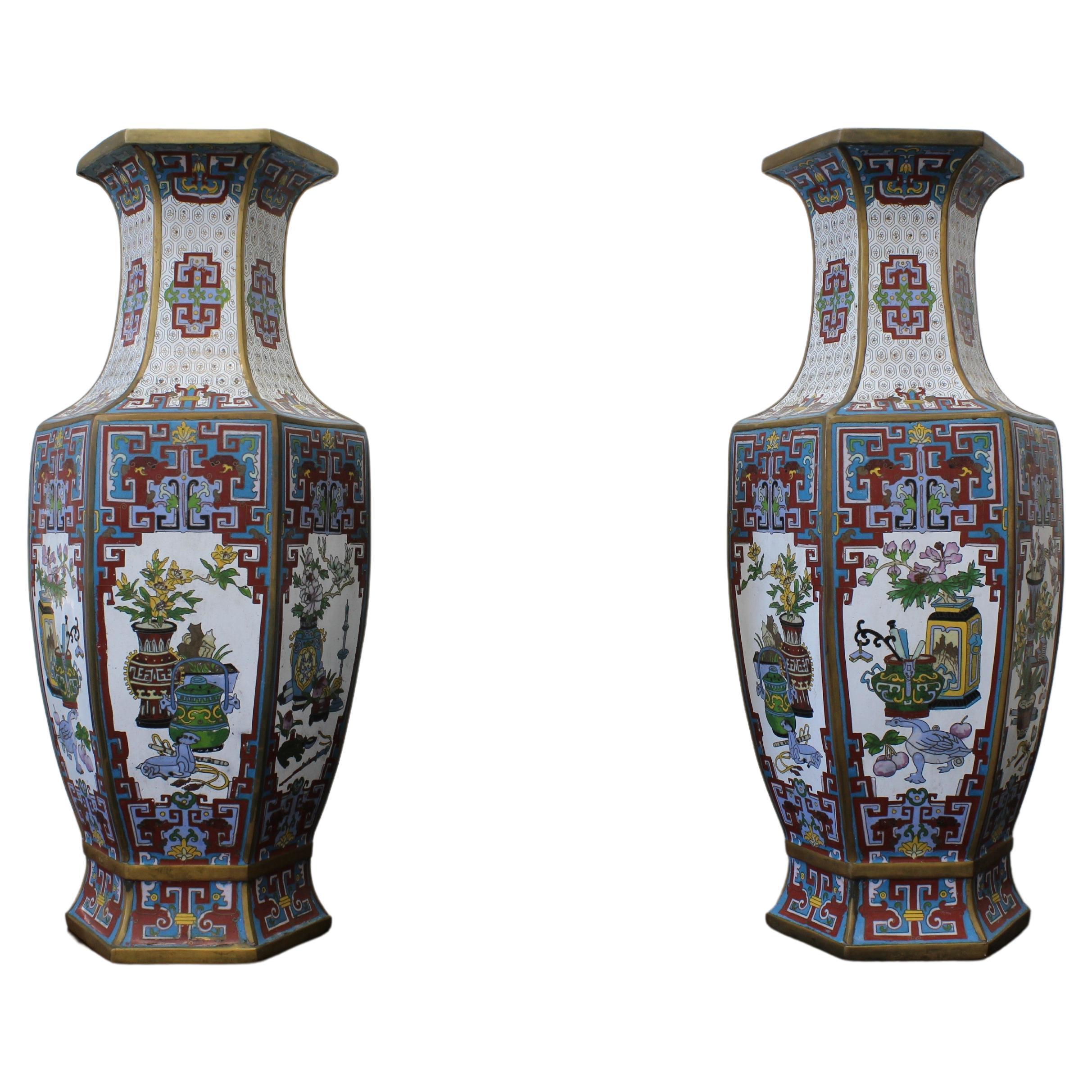 Cette paire unique de vases cloisonnés à six facettes, chacun orné du thème de 博古 (Bo Gu), illustre la beauté de l'antiquité. Les facettes présentent des cadres de fenêtres bordeaux complexes, qui rappellent les motifs de la dynastie Qing. Les