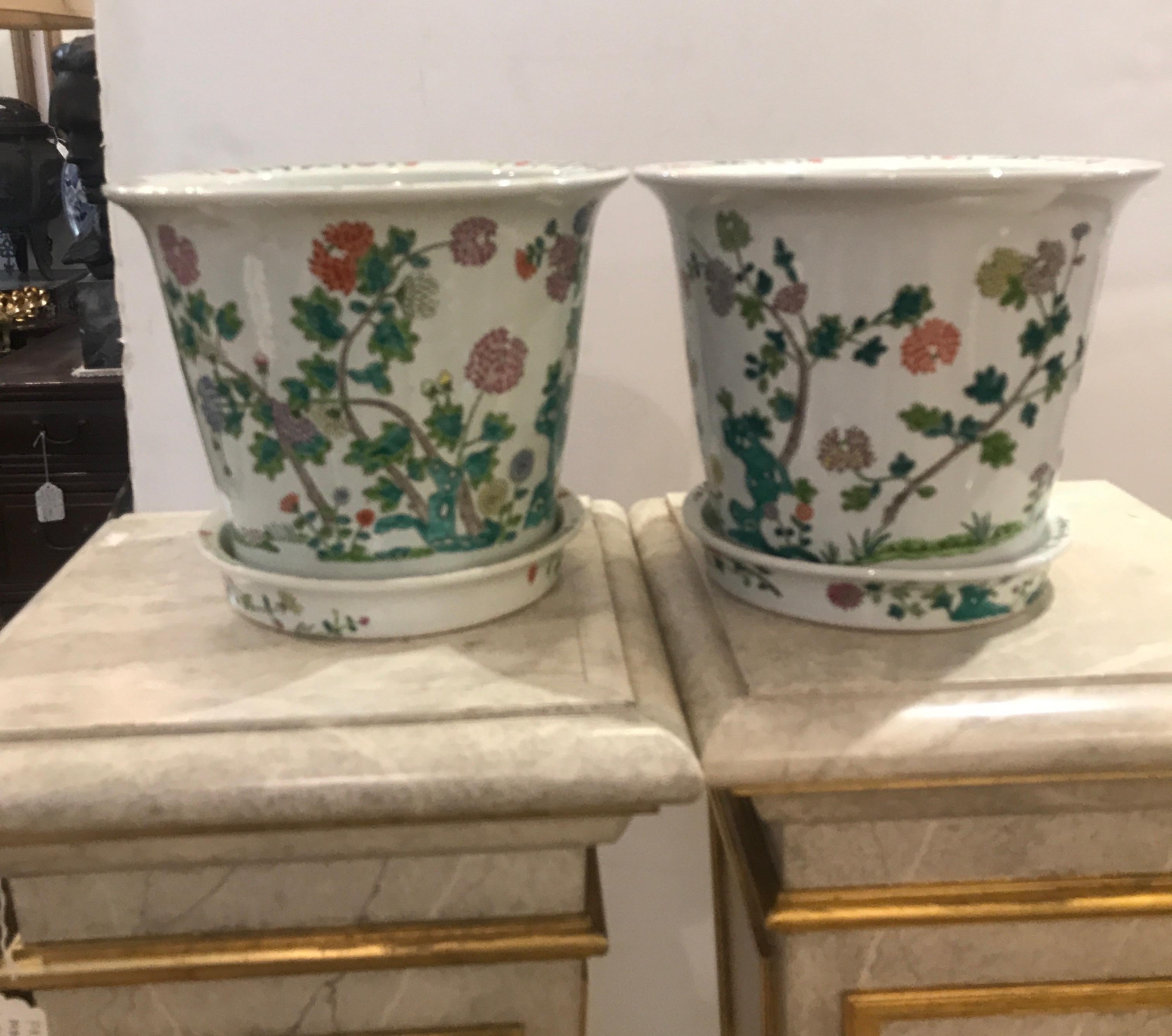A pair of hand painted Chinese porcelain planters with original underplates. Each one is hand decorated with floral and leaf branches with a white background.