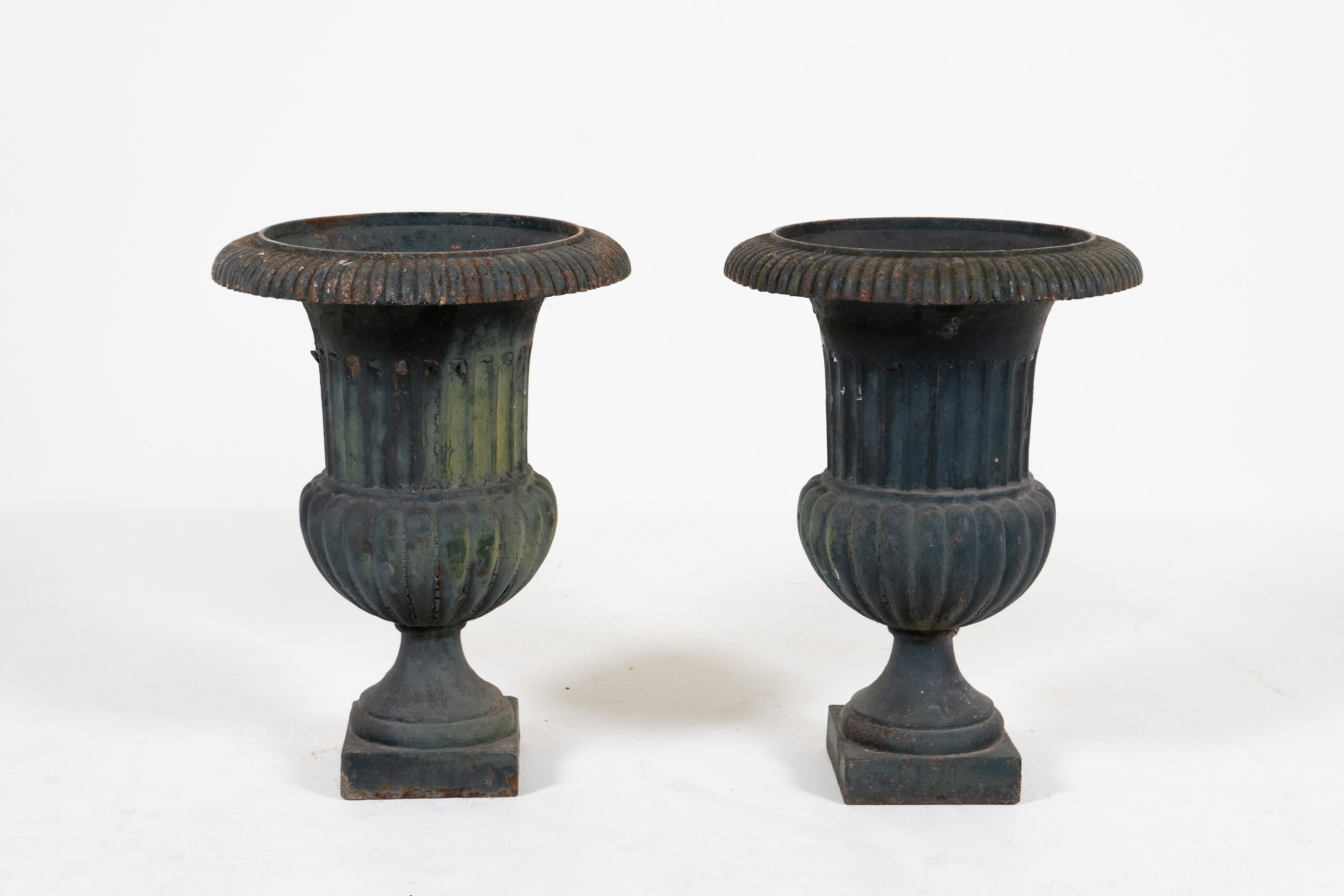 A superb pair of antique French cast iron garden urn planters circa 1880. These elegant campana jardinieres are the quintessential classic French garden urns. While originally used outdoors these can be used indoors as dramatic accessories to