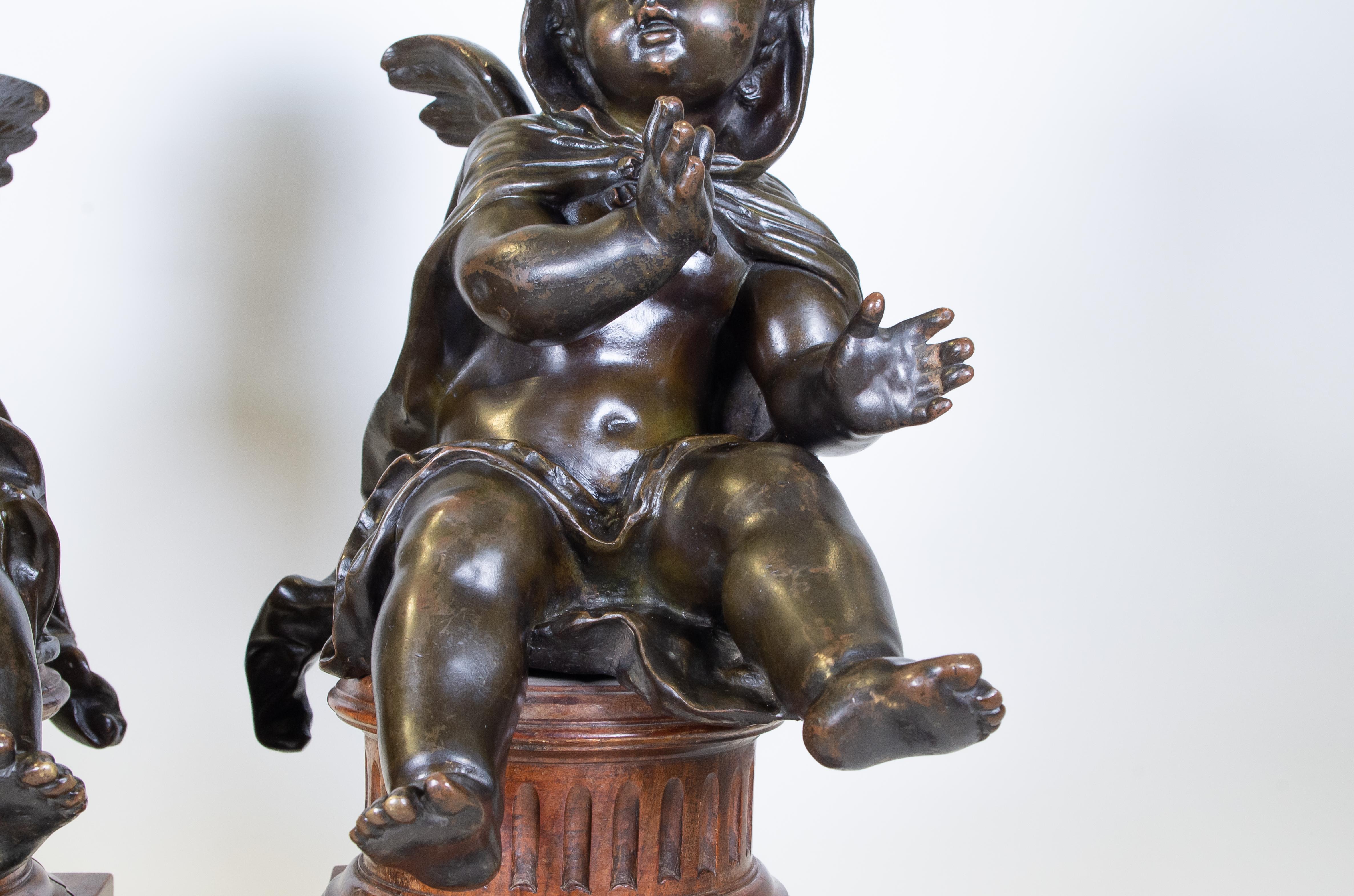 Pair of Antique French Patinated Bronze Winged Putti Seated on Fluted Plinths In Good Condition For Sale In New York, NY
