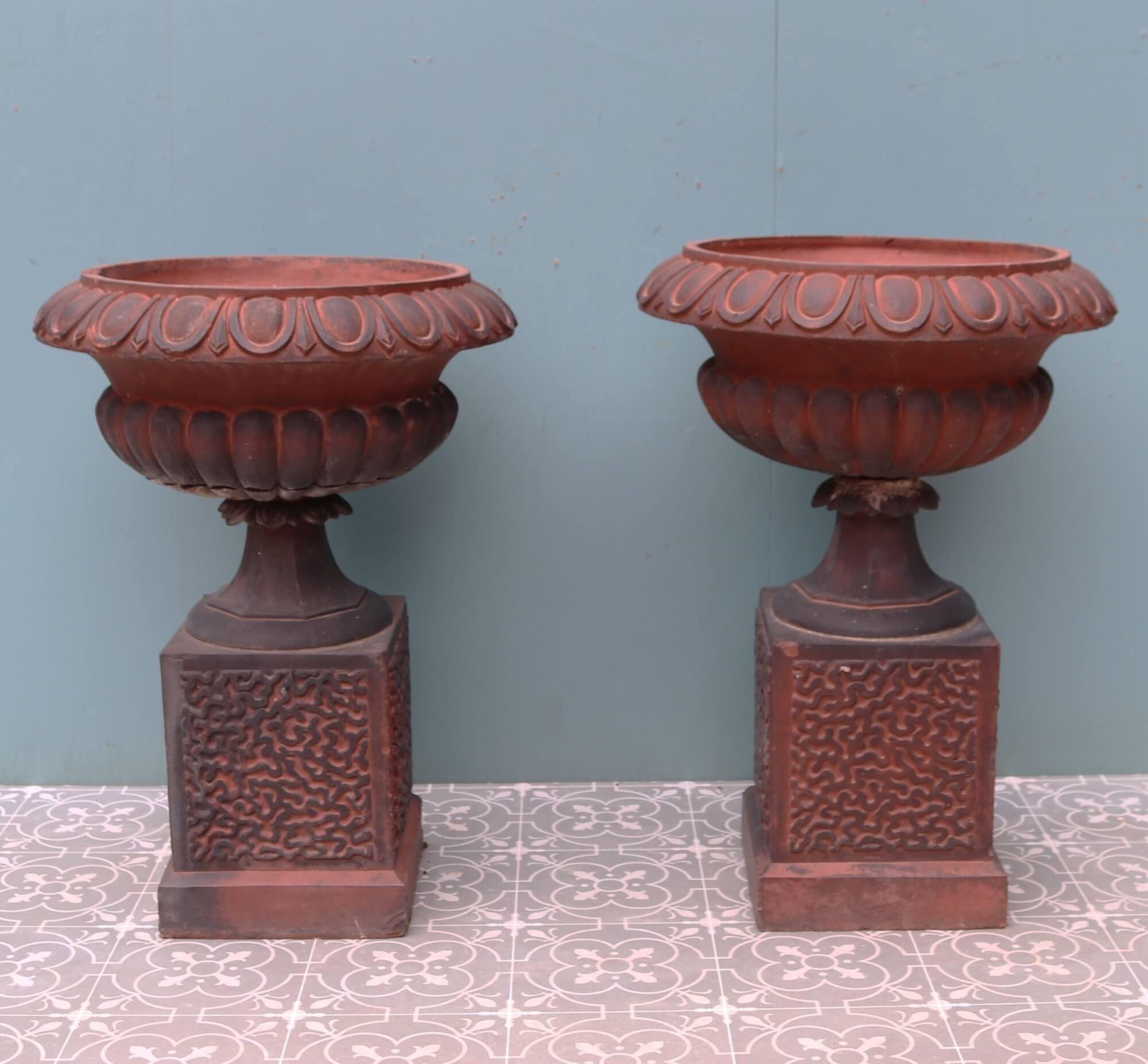Dating from the late 19th century, this pair of terracotta garden urns are a beautiful addition to a country garden. They are made in red terracotta and have a dark patination in places that indicates their age. Each are intricately designed with