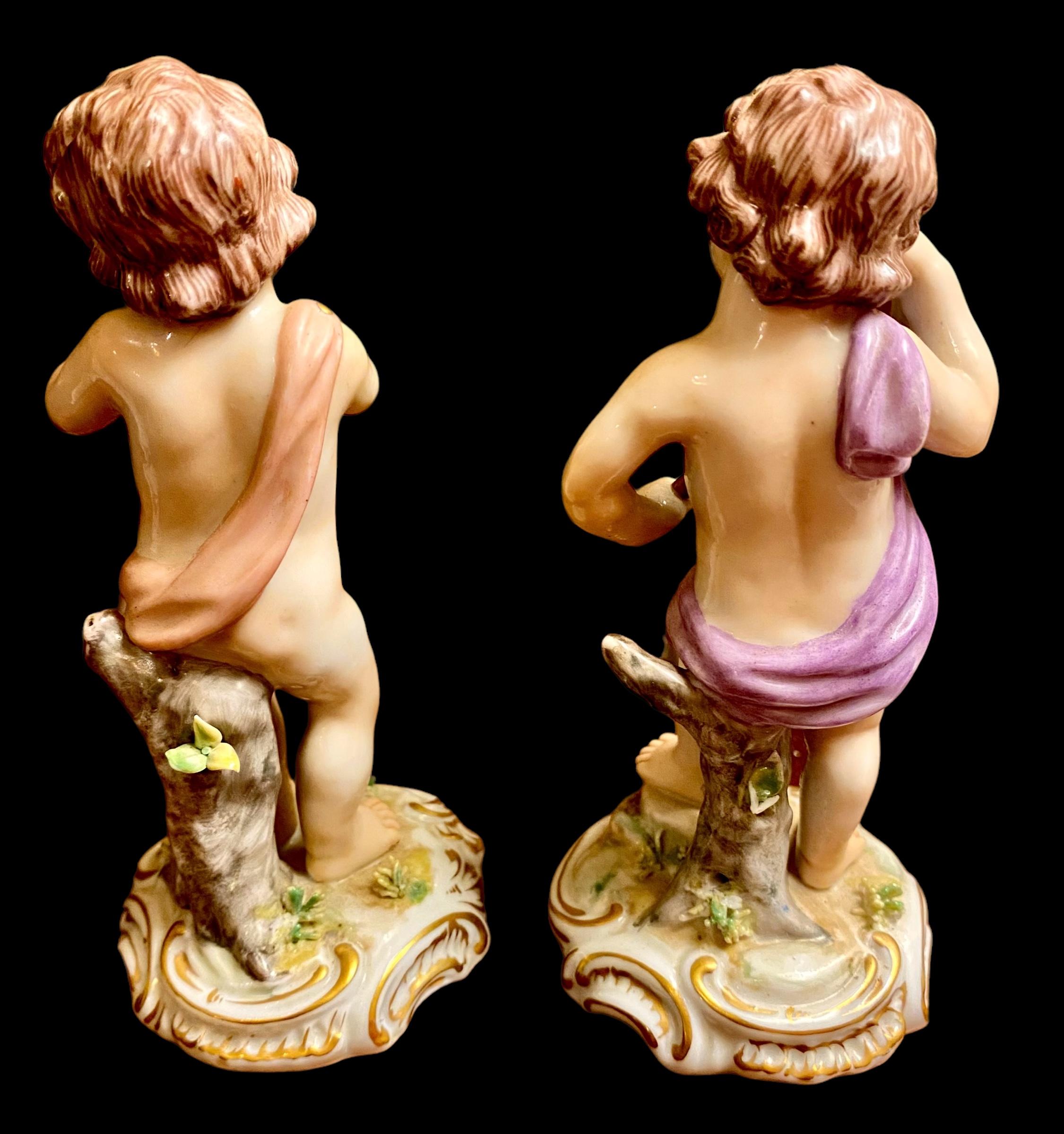 Une paire de jolies figurines de jeunes enfants avec de beaux traits de visage peints à la main. L'un tient une cloche et s'appuie sur une souche d'arbre, l'autre un enfant avec des feuilles florales. Une si belle attention aux moindres