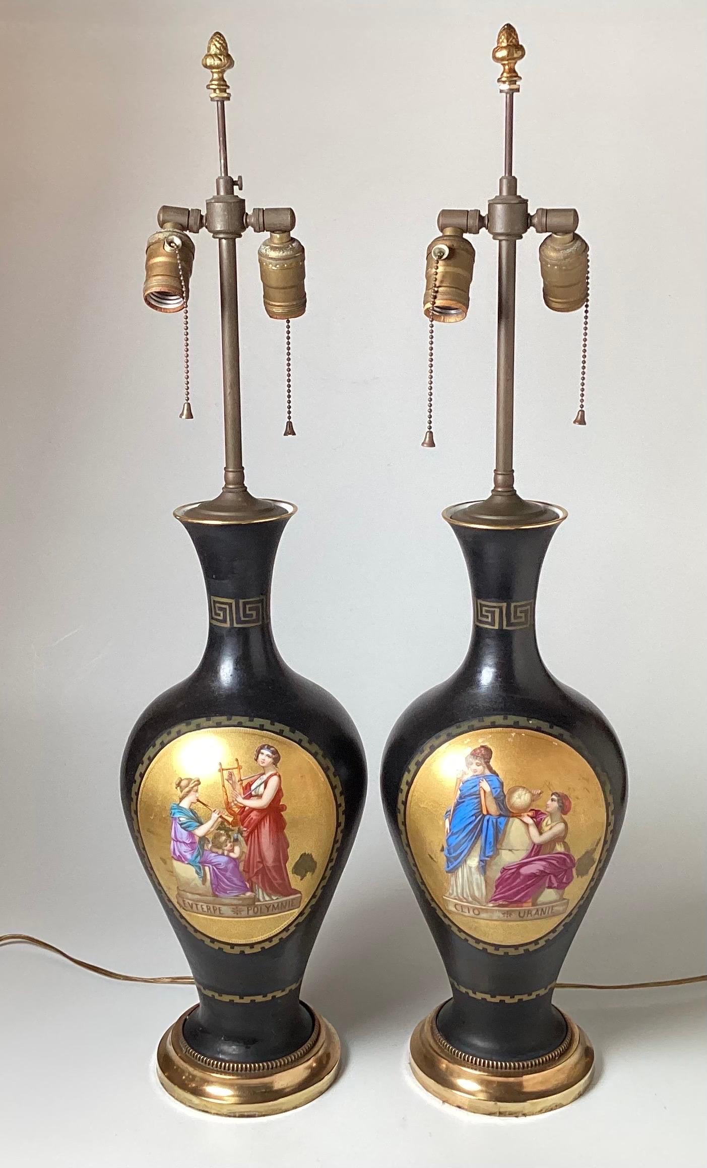 A Pair of Hand Painted neoclassical French Porcelain lamps. The porcelain urns with gilt cartouches depicting Greek Muse's Evterpe, Polymnie, Clio and Uranie... Each lamp has two sockets for extra light, with a polished brass base. The lamps are