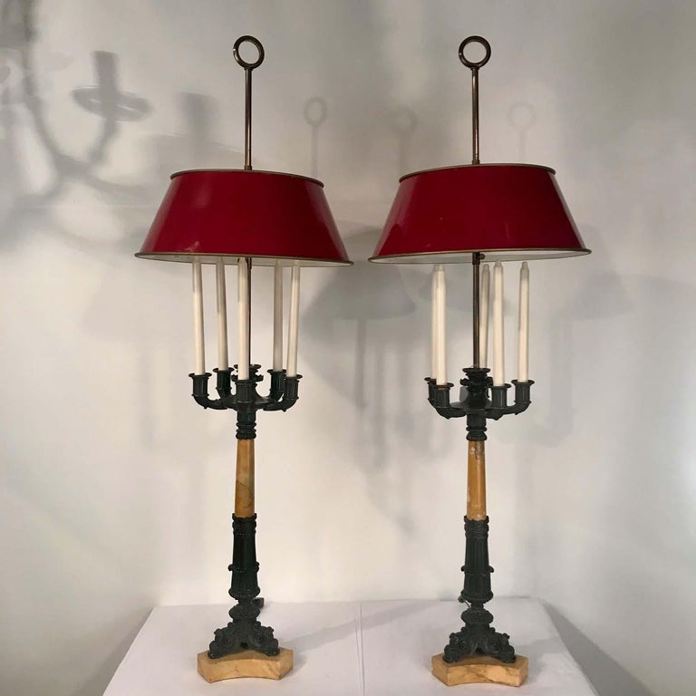 A large pair of Charles X bronze and marble five-light candelabra now fitted as table lamps. This striking pair combine honey-colored Siena marble and dark crisp scrolling bronze in a manner both warm and powerful. , Each with a marble column raised