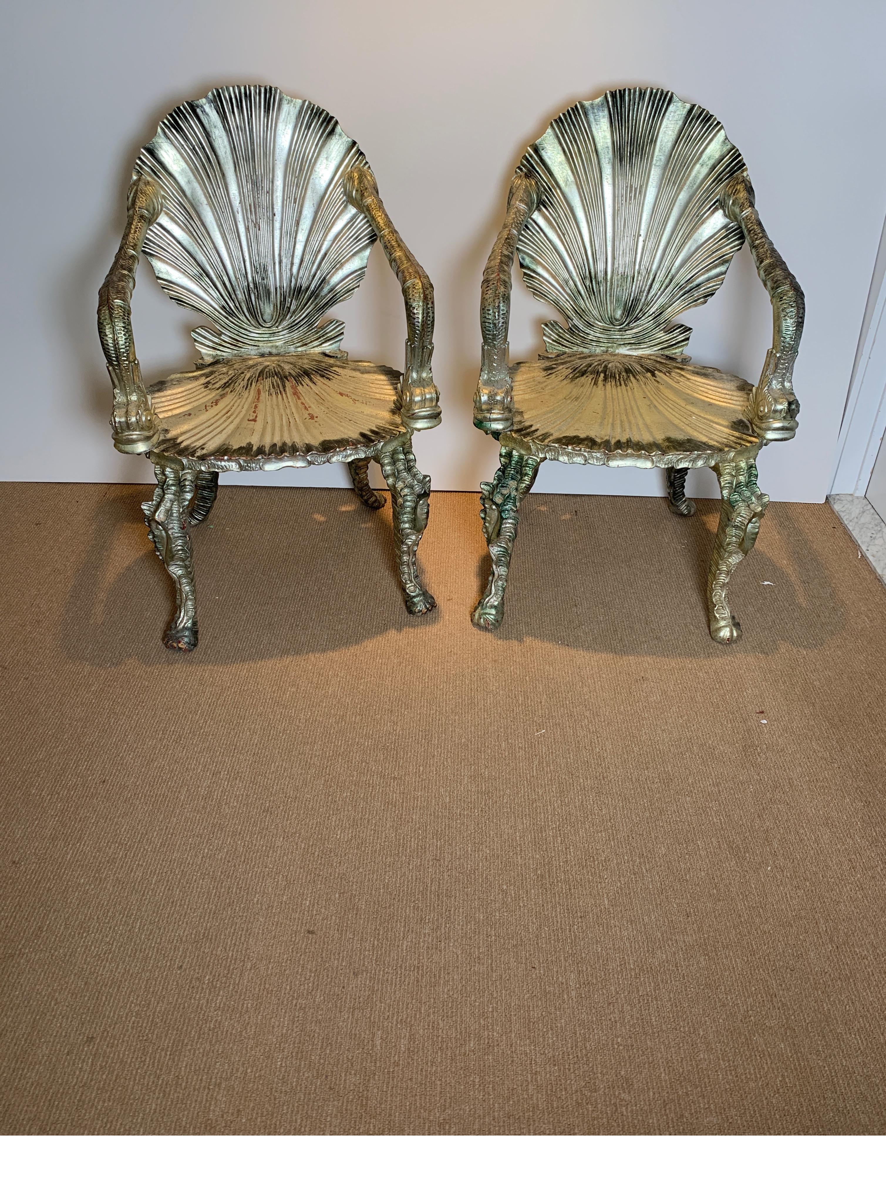 A pair of Venetian carved wood silver leaf grotto chairs. Whimsically carved chairs with shell back and seat, dolphin arms and legs in a sea horse tail motif. Italy, early 20th century.

 