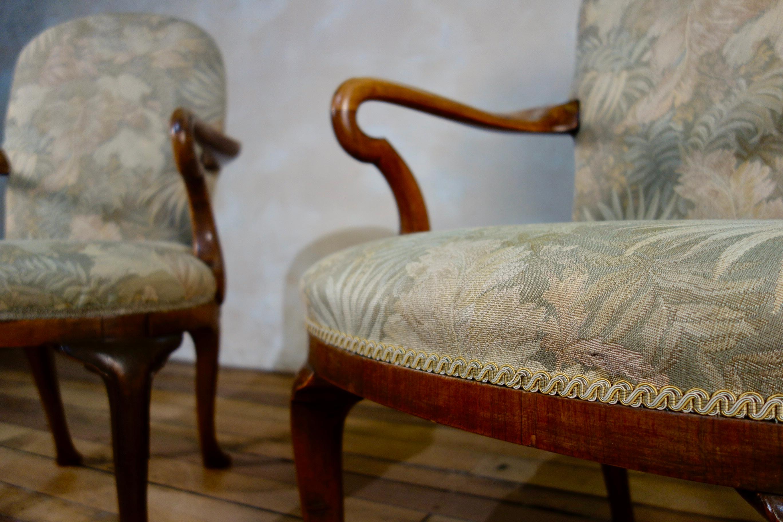 A pair of George I style armchairs, featuring walnut shepherd crook arms and rounded upholstered back. Raised on raking rear legs with front cabriole legs - sat on pad feet.    This is one pair from a set of three pairs of identical chairs, with