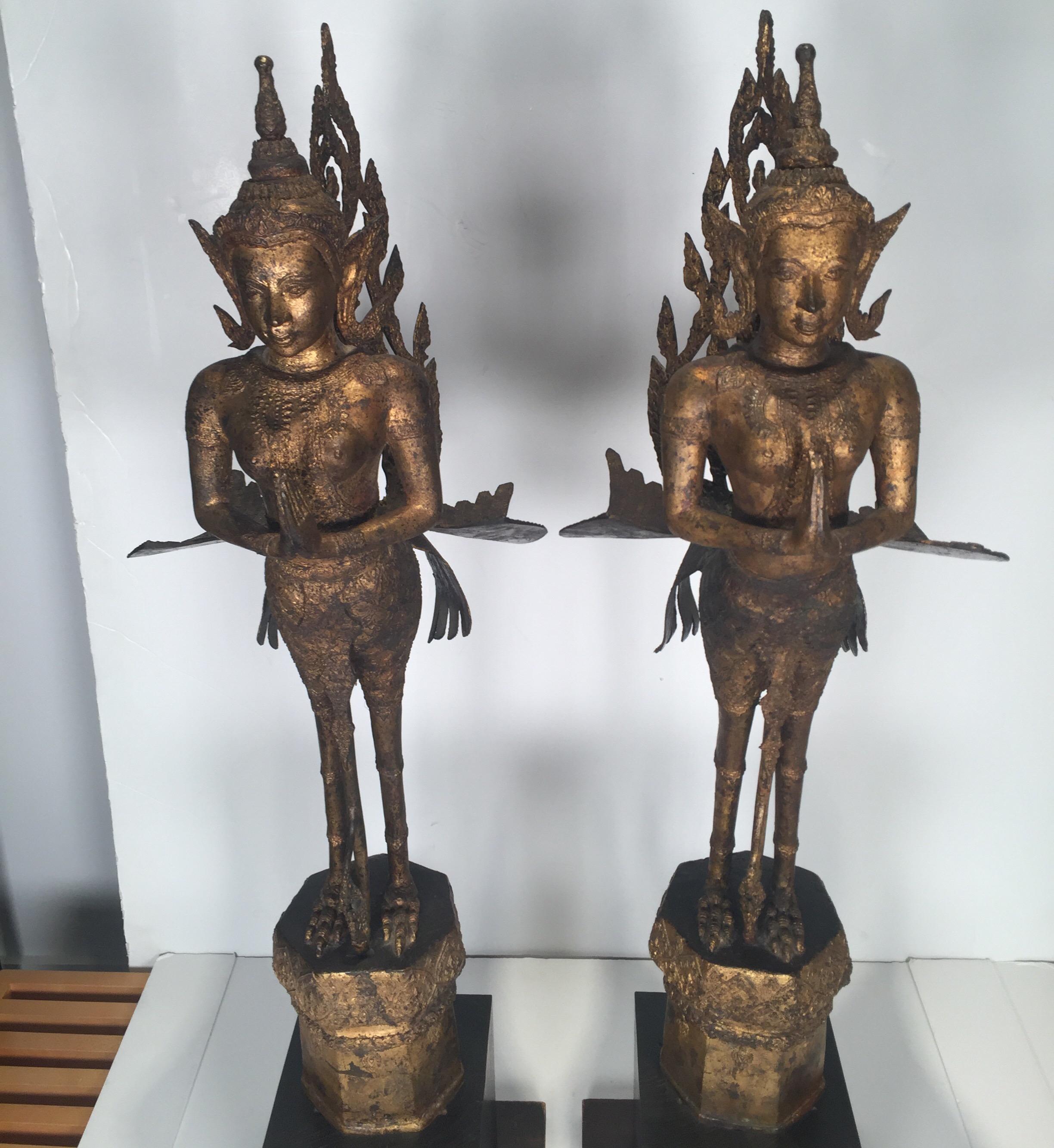 The bronze sculpture with patinated gilt finish with expected age wear. Each with a later black wood base. Thailand, early 20th century, 1920.