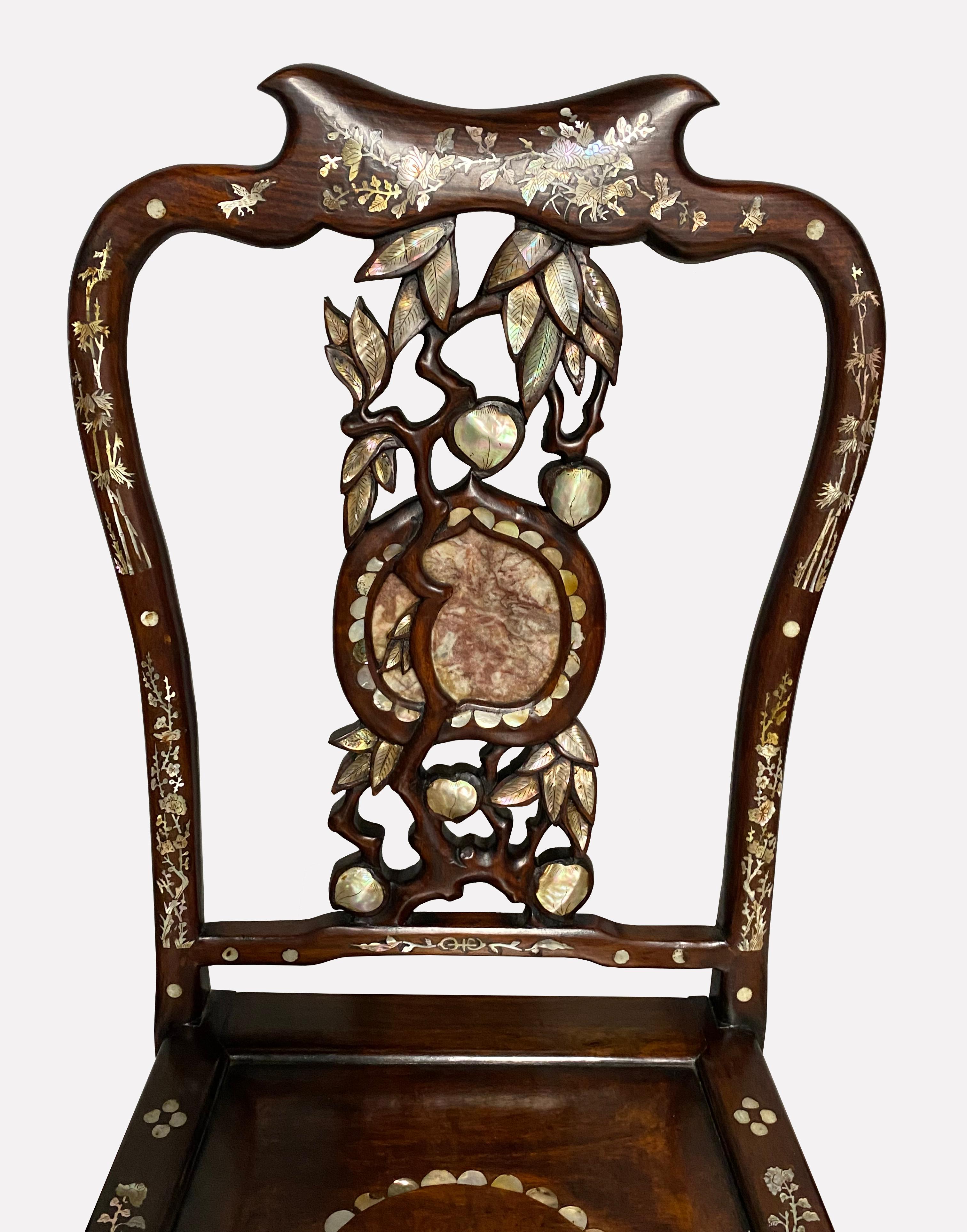 
A most elegant pair of antique Vietnamese export rosewood fiddle back chairs with exquisite inlaid detail and classic mitered mortise and tenon construction. The vertical back stretcher is an organic carving of an old peach bough with the leaves