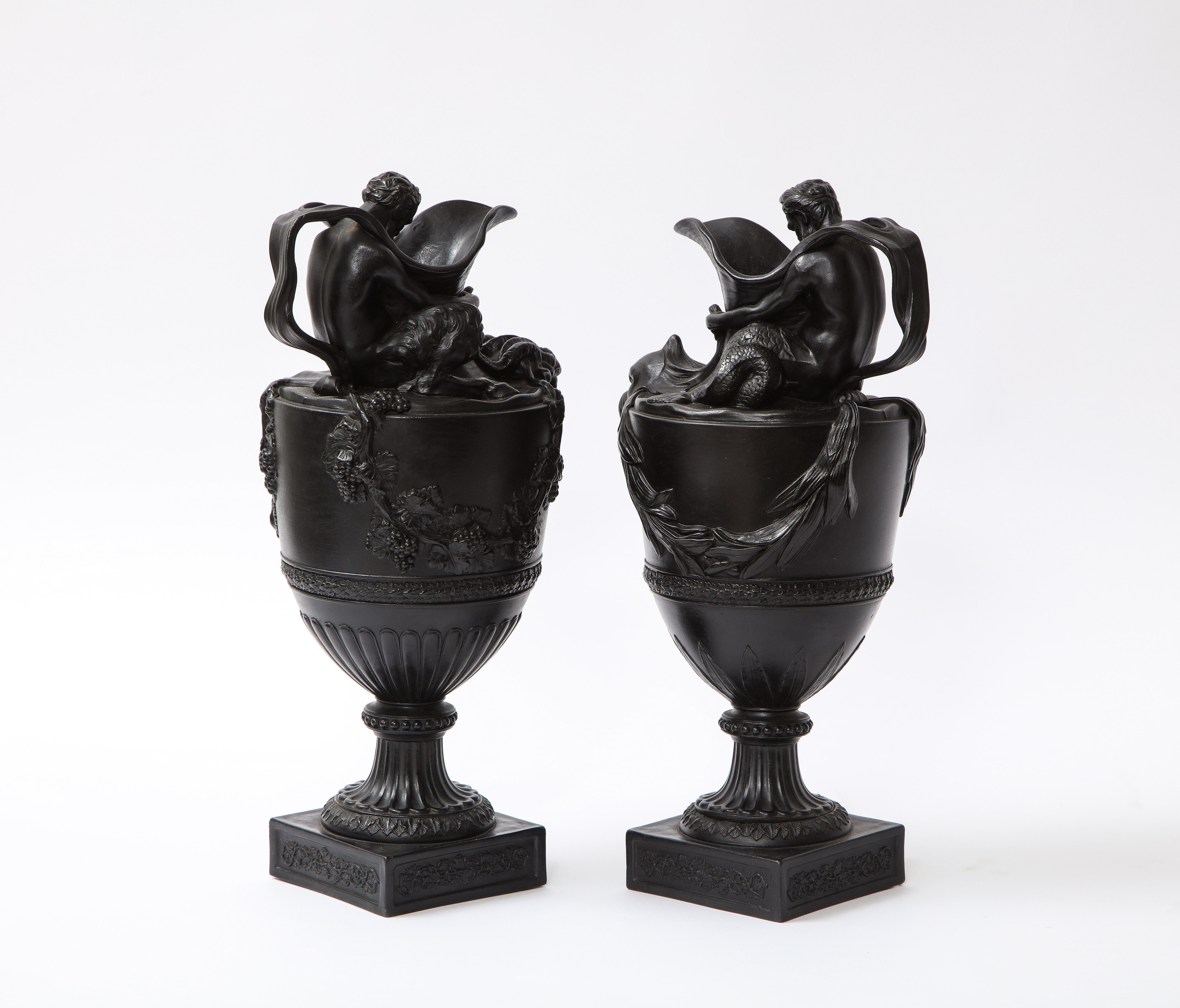 A fabulous pair of antique neoclassical period early Wedgwood black basalt water and wine ewers emblematic of water and earth. These are a popular and well-known model of Wedgwood ewers named 